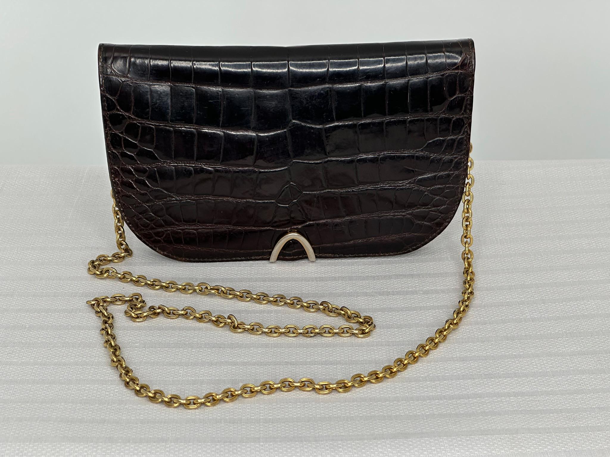 Bolso bandolera Guy Laroche Paris de cocodrilo esmaltado marrón chocolate con herrajes dorados. Desde los años 90, este pequeño bolso puede llevarse como bolso de mano o como bandolera. Bolso con solapa y cierre en V invertida de metal dorado en el