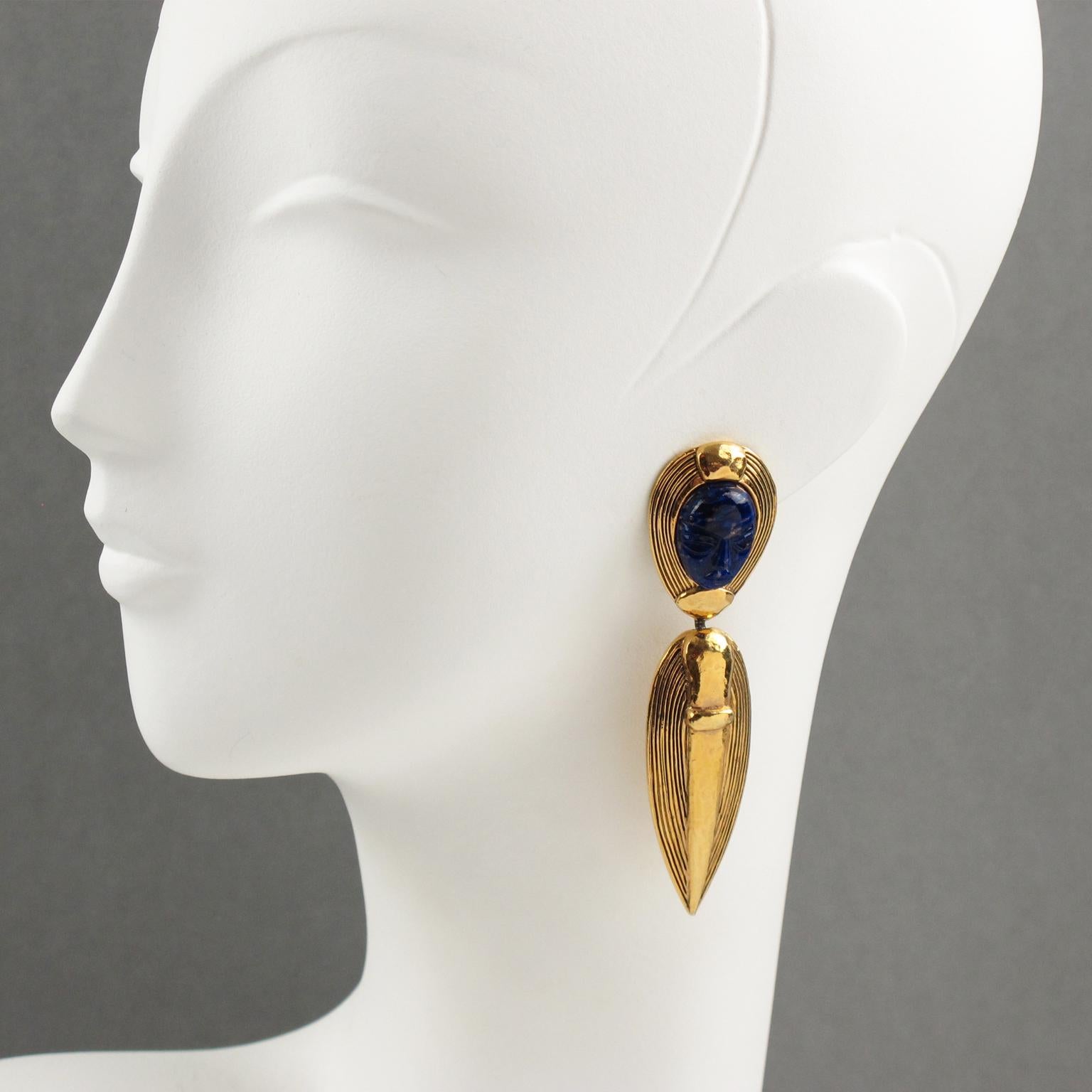 Elegant Guy Laroche Paris signed clip-on earrings. Dangling shape featuring sort of South American inspired design, mostly Pre-Colombian with carved and textured gilt metal, ornate with Lapis Lazuli glass cabochon with face carving. Engraved