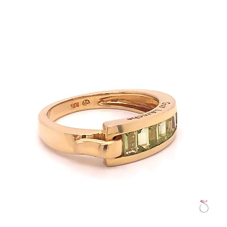 French Designer Guy laroche Peridot band ring in 18k yellow gold. This beautifully designed band features a gorgeous line of channel set green peridot Gemstones. The band has a unique hook design on the side. The ring is masterfully crafted in 18k