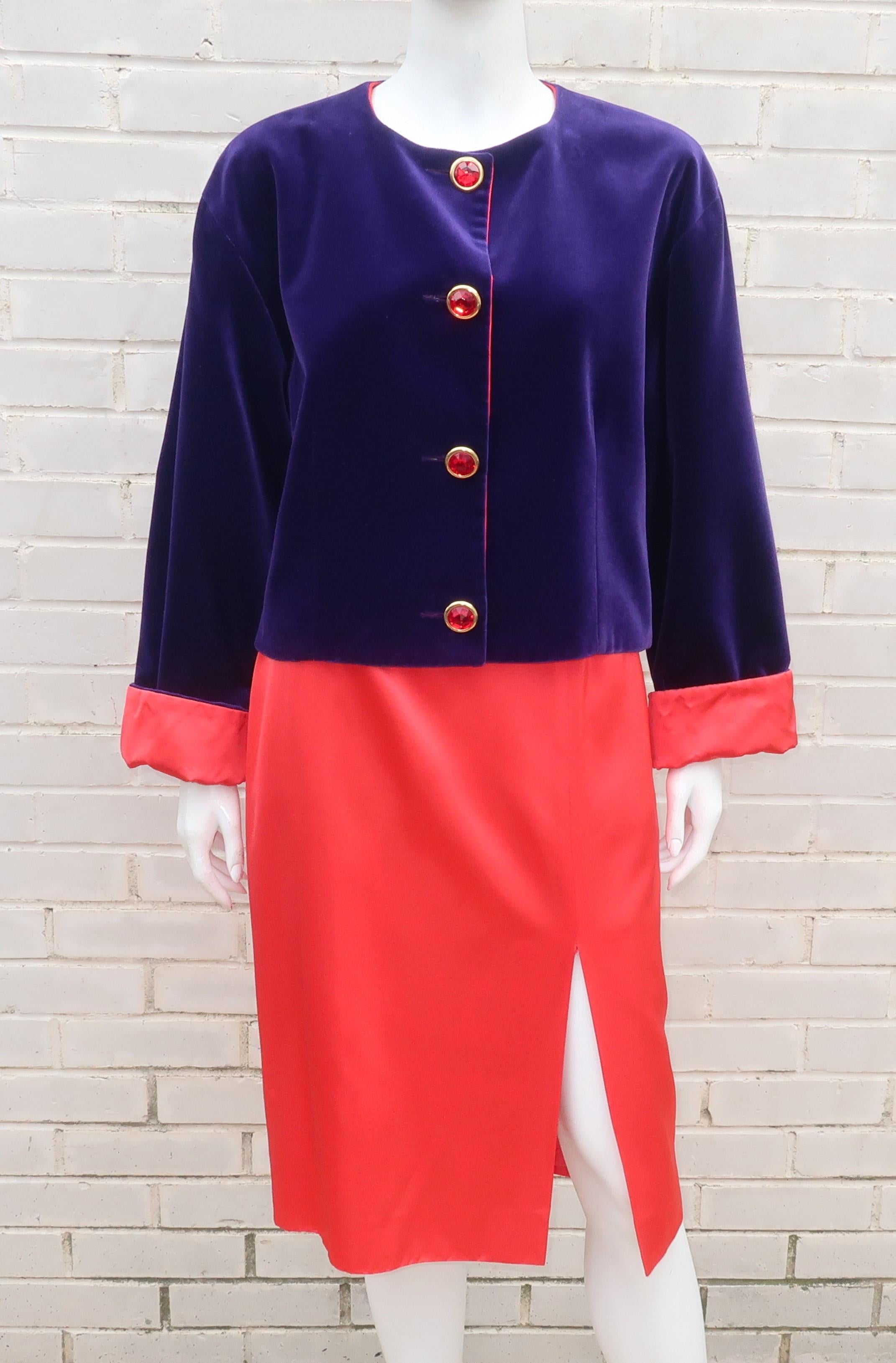 Traje de dos piezas Guy Laroche con chaqueta recortada de terciopelo púrpura real forrada de satén rojo tomate acompañada de falda a juego.  La chaqueta sin cuello tiene una silueta cuadrada con botones facetados en la parte delantera y mangas que