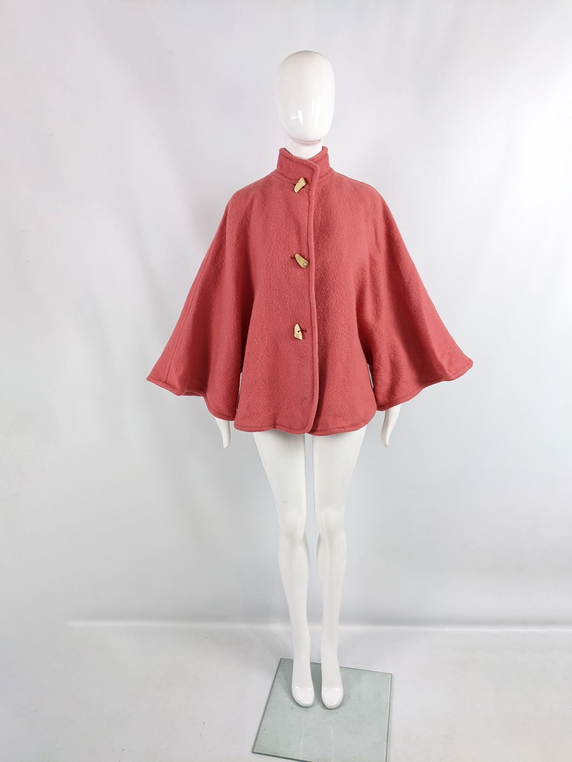 An incredible vintage womens coat from the 80s by luxury French fashion designer, Guy Laroche. In a coral pink thick but fairly lightweight wool and mohair fabric. It has huge wide cut sleeves giving a cape like feel and toggle fastenings down the