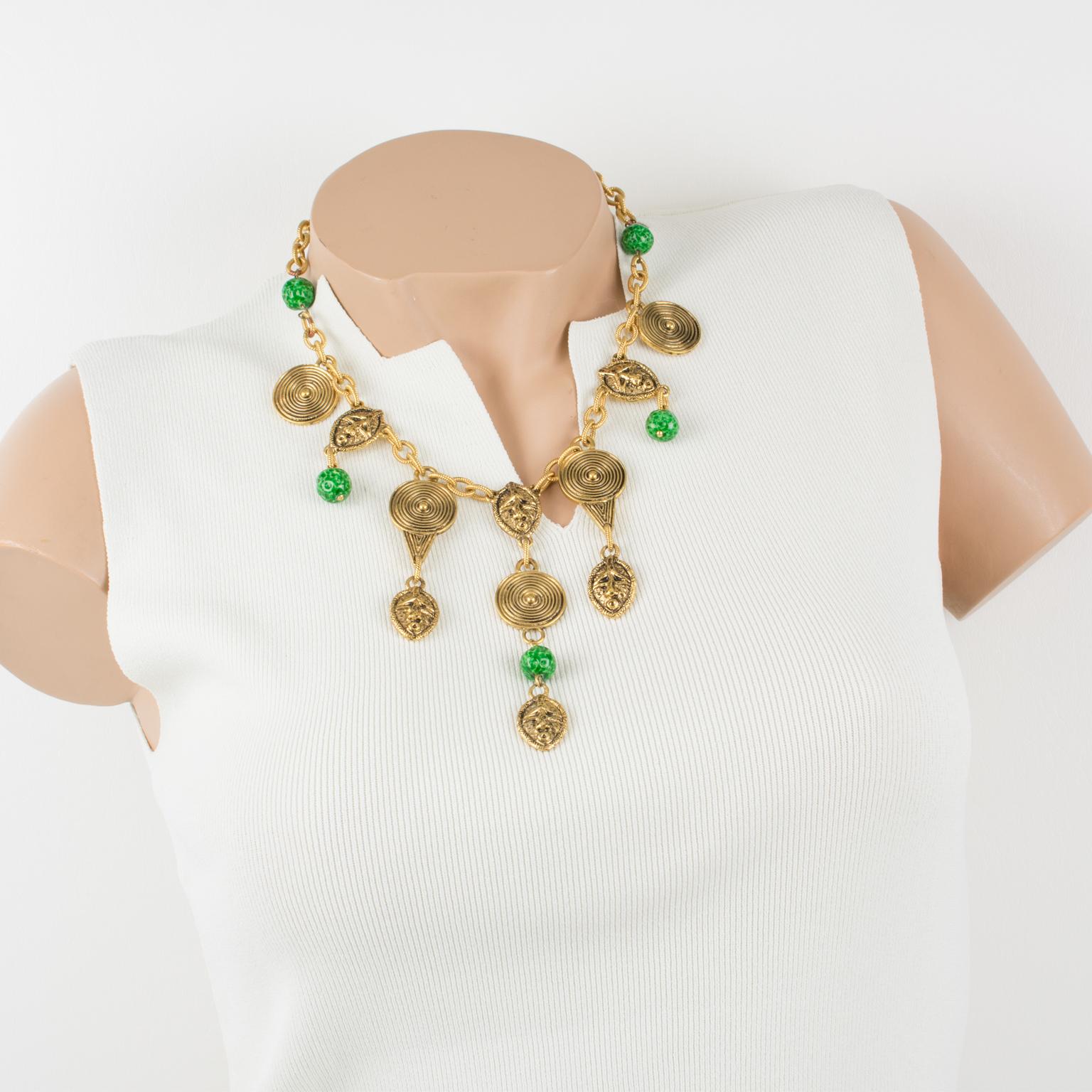 Ce magnifique collier ras-de-cou tribal Guy Laroche Paris est composé de breloques en forme de masques et de boucliers d'inspiration africaine, probablement Massai, en métal doré sculpté et texturé, orné de perles de céramique vertes ressemblant à