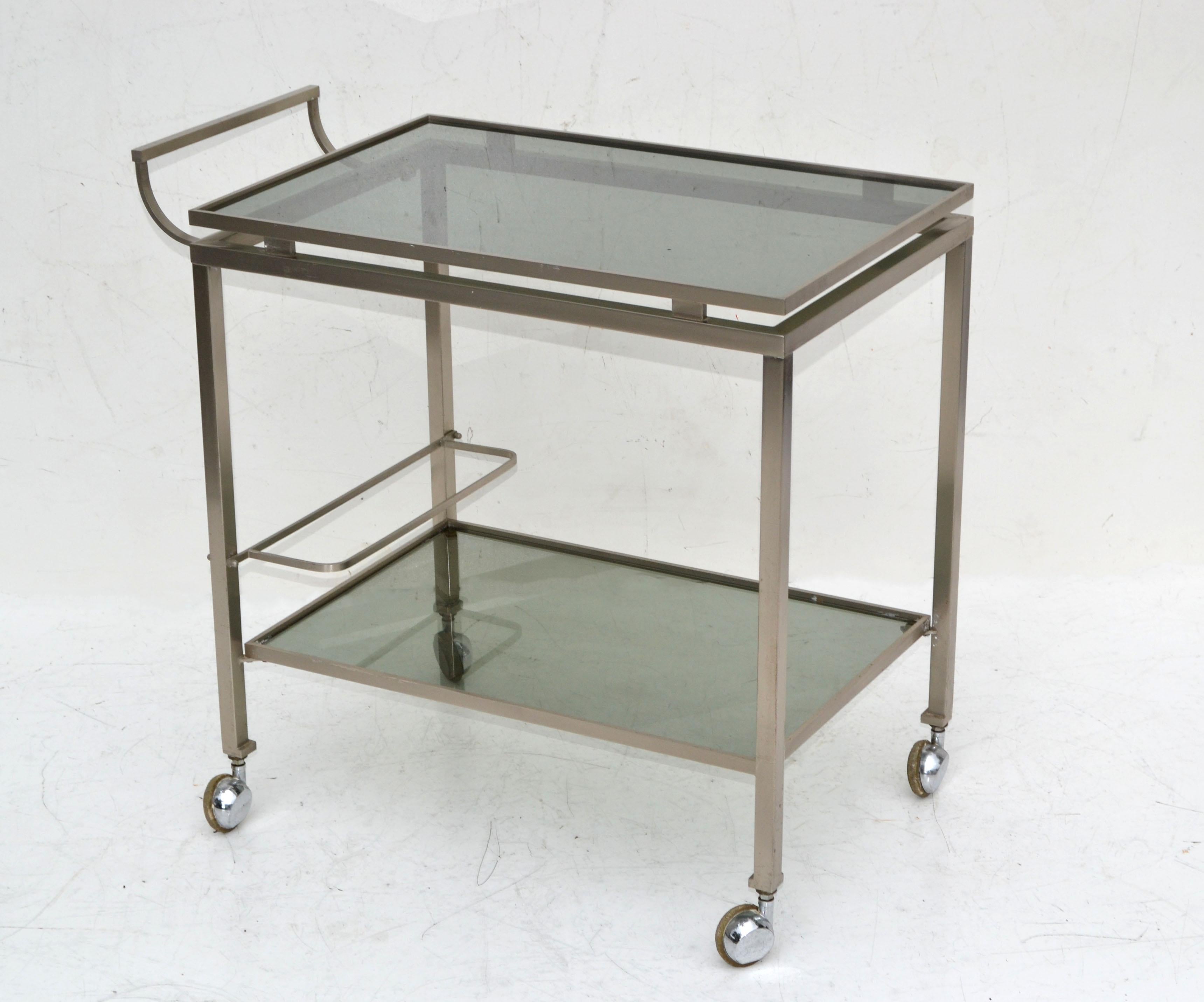 1 of 2 French bar cart two-tier by Guy Lefevre for Maison Jansen. 
1960 in Chrome with smoked glass shelves and all original wheels.
Measures: 24 Inches length without the handle, 29 inches length overall, 27.5 inches height overall, 25.3/4 inches