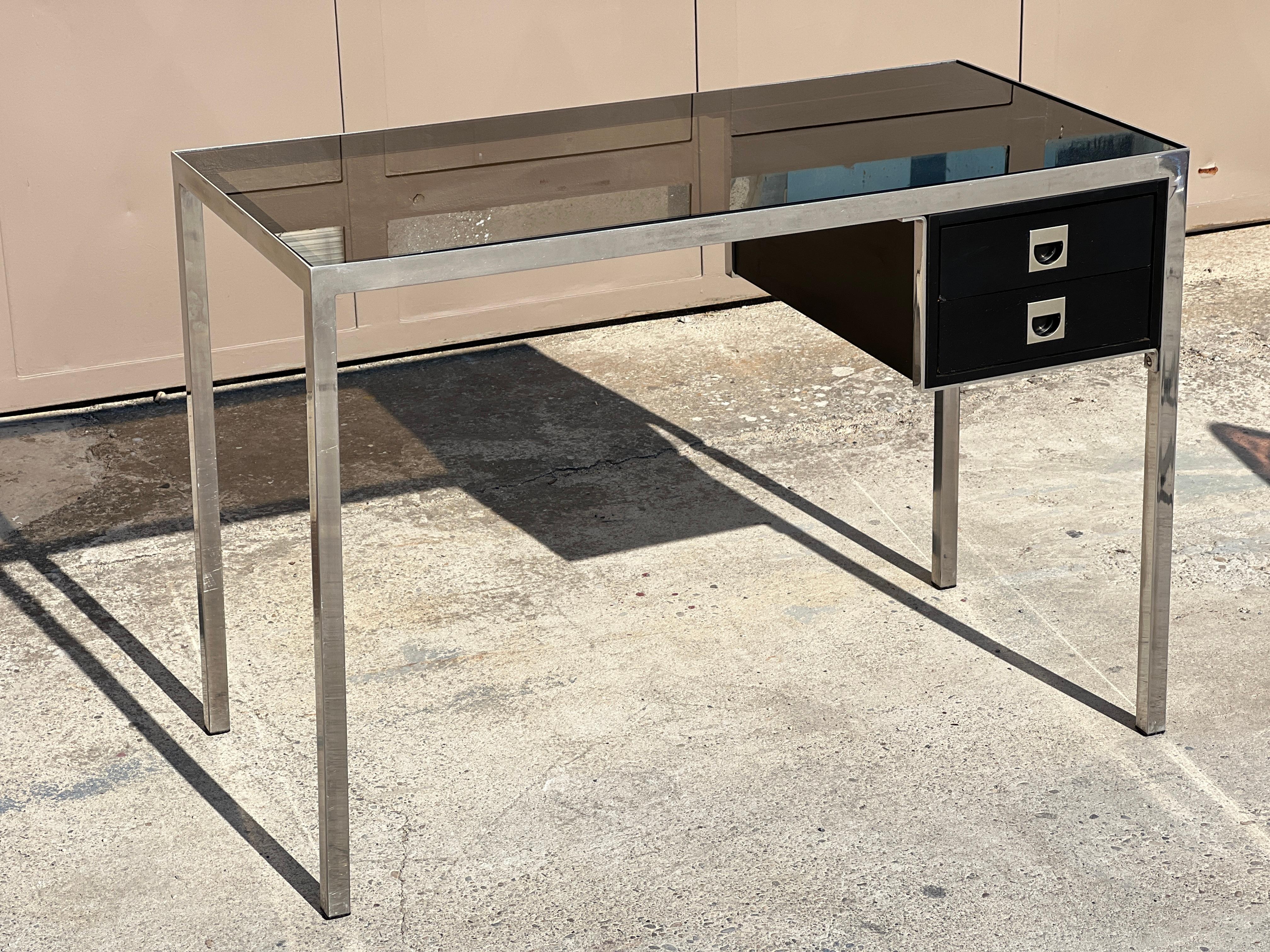 Guy Lefèvre desk with 2 drawers and folding chairs in plexiglas, 1970
Small brown desk, chrome-plated metal base, square section
square section, smoked glass top, lateral box opening with two
opening with two drawers, brown.