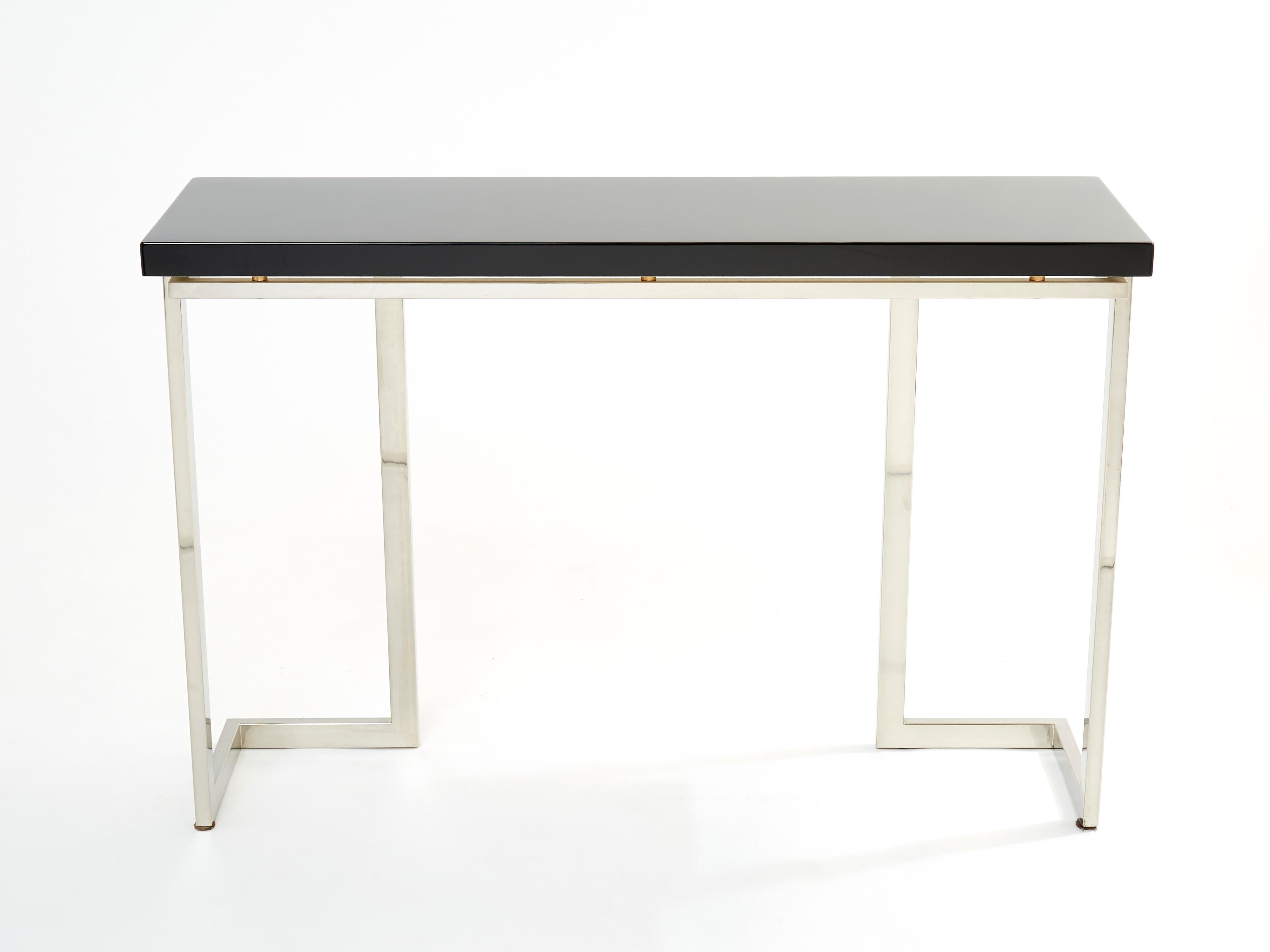 With a shining black lacquered top, and sharply geometric chrome legs and structure,, this console table carries a futuristic mid-century aesthetic into the contemporary home. Its boxy yet sophisticated style is typical of both the 1970s and French