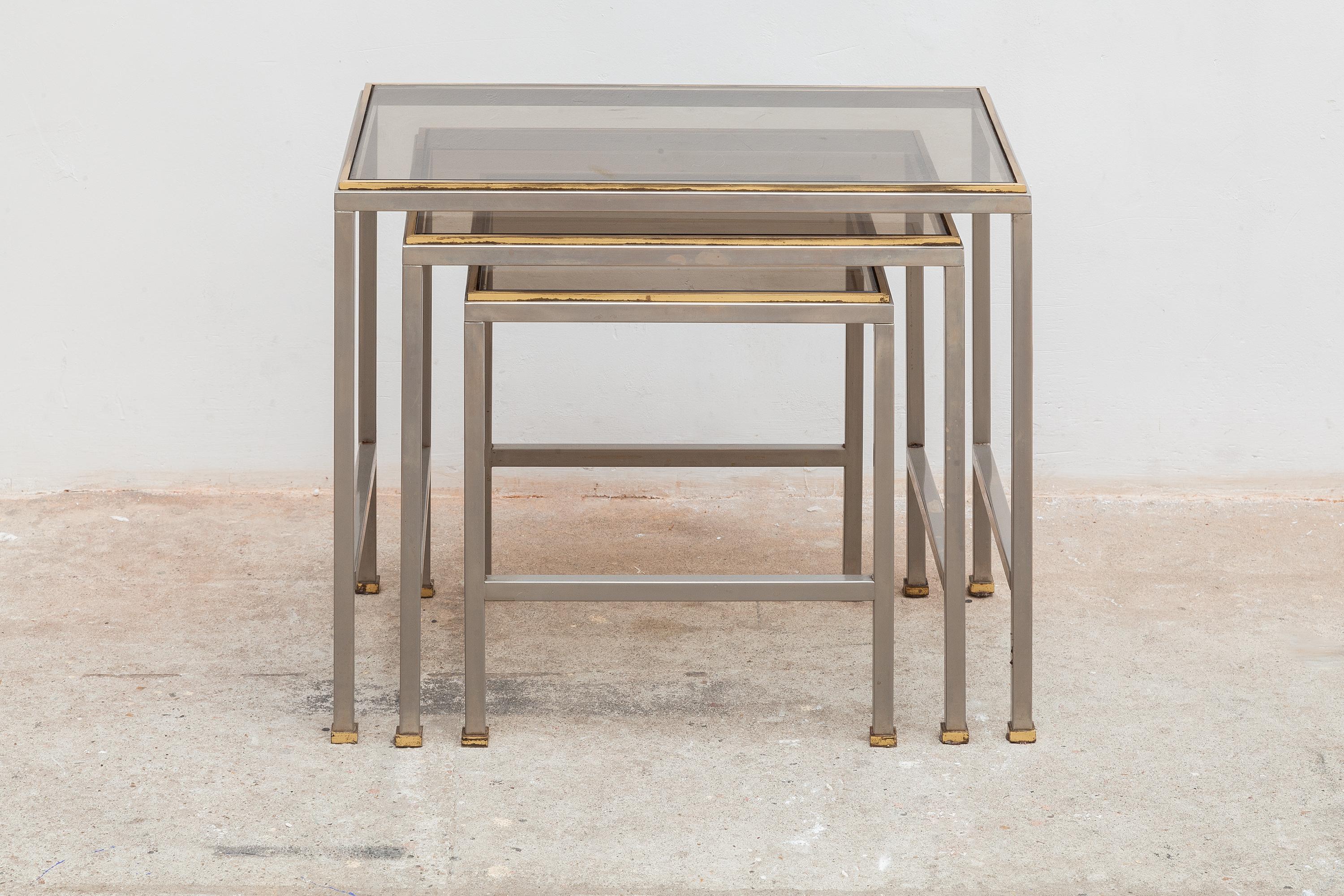 Elegant nest of three modernist tables in silver and brass tone frames with smoked glass tops designed by Guy Lefevre for Maison Jansen, 1970s.
Dimensions: Small 32 W x 34 H x 32 D cm, Med: 42 W x 38 H x 32 D cm, large: 52 W x 42 H x 32 D cm.