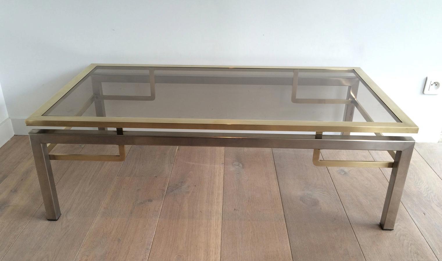 This coffee table is made of brushed steel and brass. This is a very nice model with 2 side shelves under the main glass and which quality is really good. This cocktail table was made by famous French designer Guy Lefèvre for Maison Jansen, circa