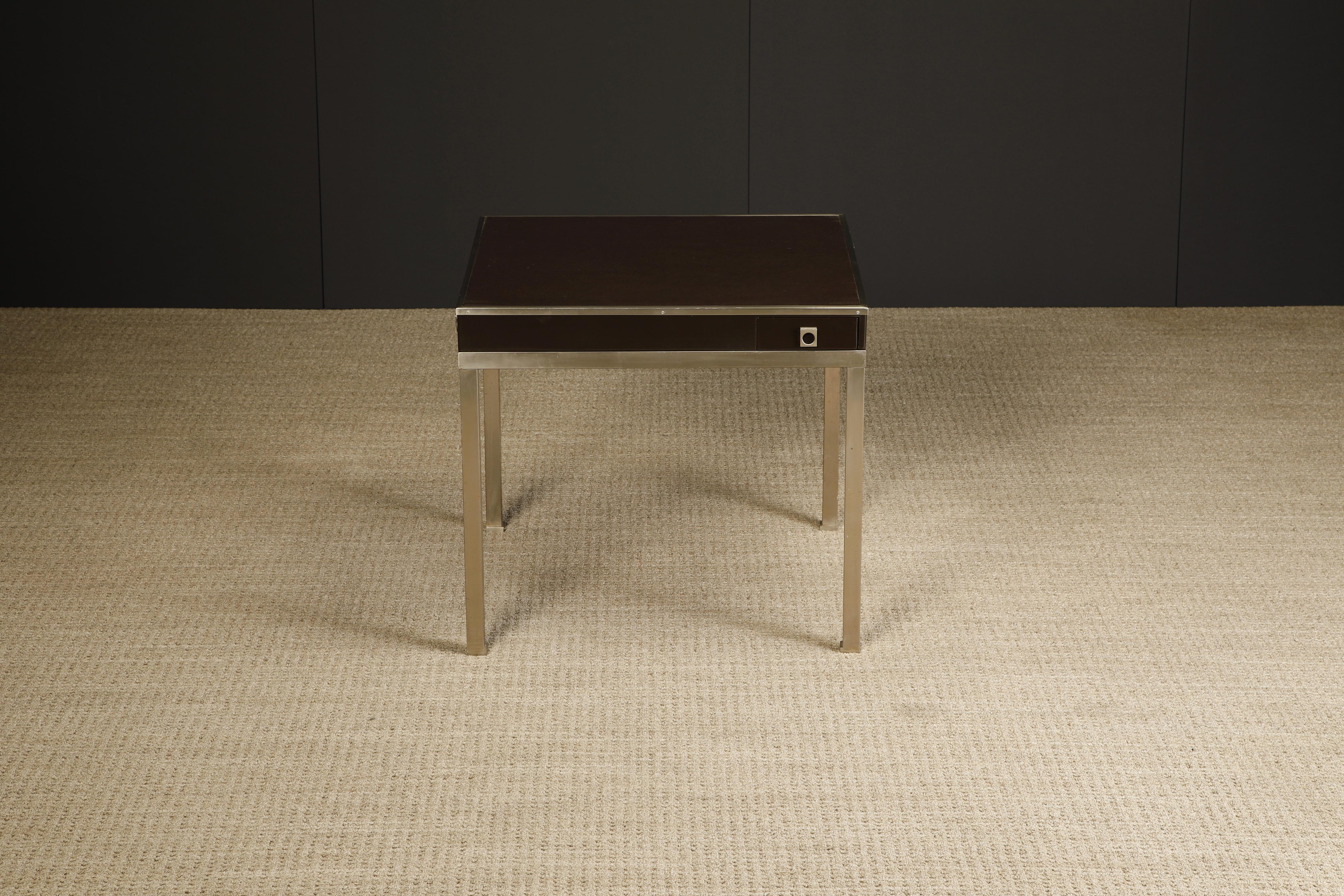 This refined game table, which also works as a smaller dining table or center table, is by Guy Lefevre for Maison Jansen, circa 1970s France. Featuring a square leather top over lacquered brown case with brushed steel trim, legs and drawer rings,