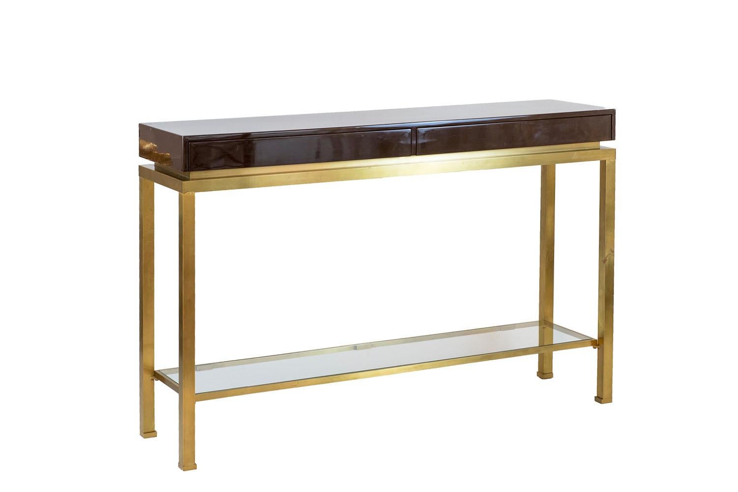 Guy Lefèvre for Maison Jansen, attributed to.

Rectangular console table in lacquer and brass opening by two front drawers. It stands on four square section feet linked with each other by a stretcher made of a glass shelf.
Upper part in dark brown