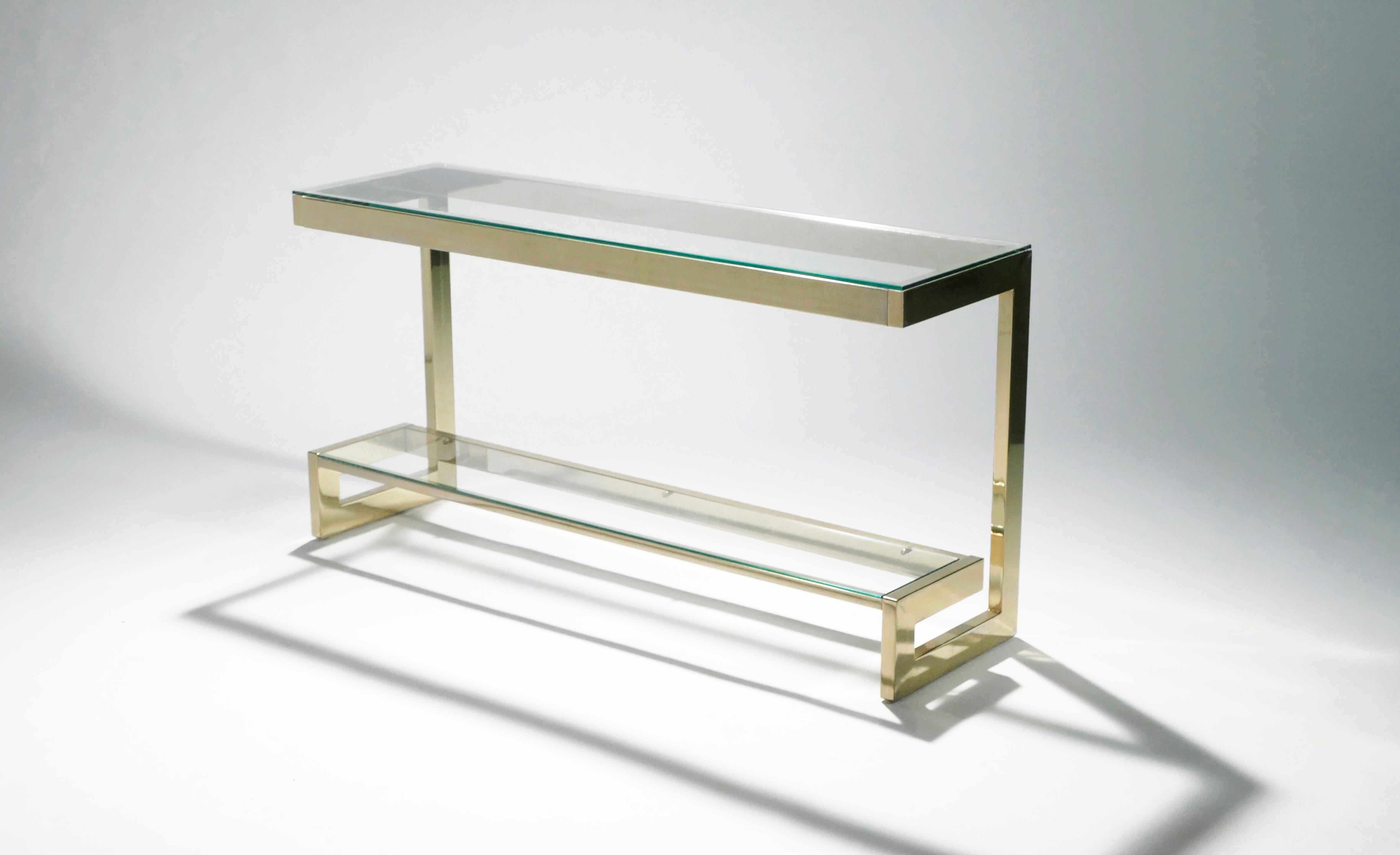 Minimalistic lines become lighter than air in this 1970s console table. Crafted by Guy Lefevre for Maison Jansen, it features sleek expanses of crystal-clear glass set into a structured gold-tone brass frame. The floating two-tier design is