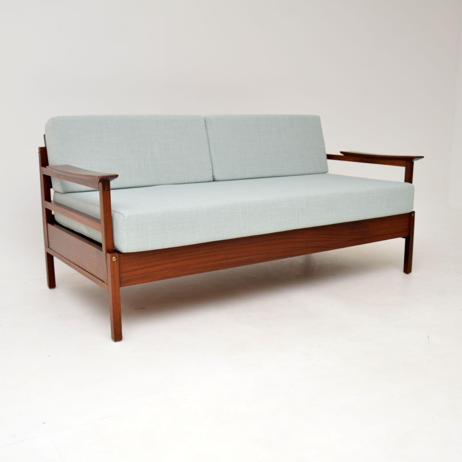 A stylish and very rare vintage ‘Gambit’ sofa bed by Guy Rogers. This was made in England during the 1960’s.

The frame is solid wood, which has gorgeous grain patterns and a beautiful, rich colour. The cushions have been newly made and