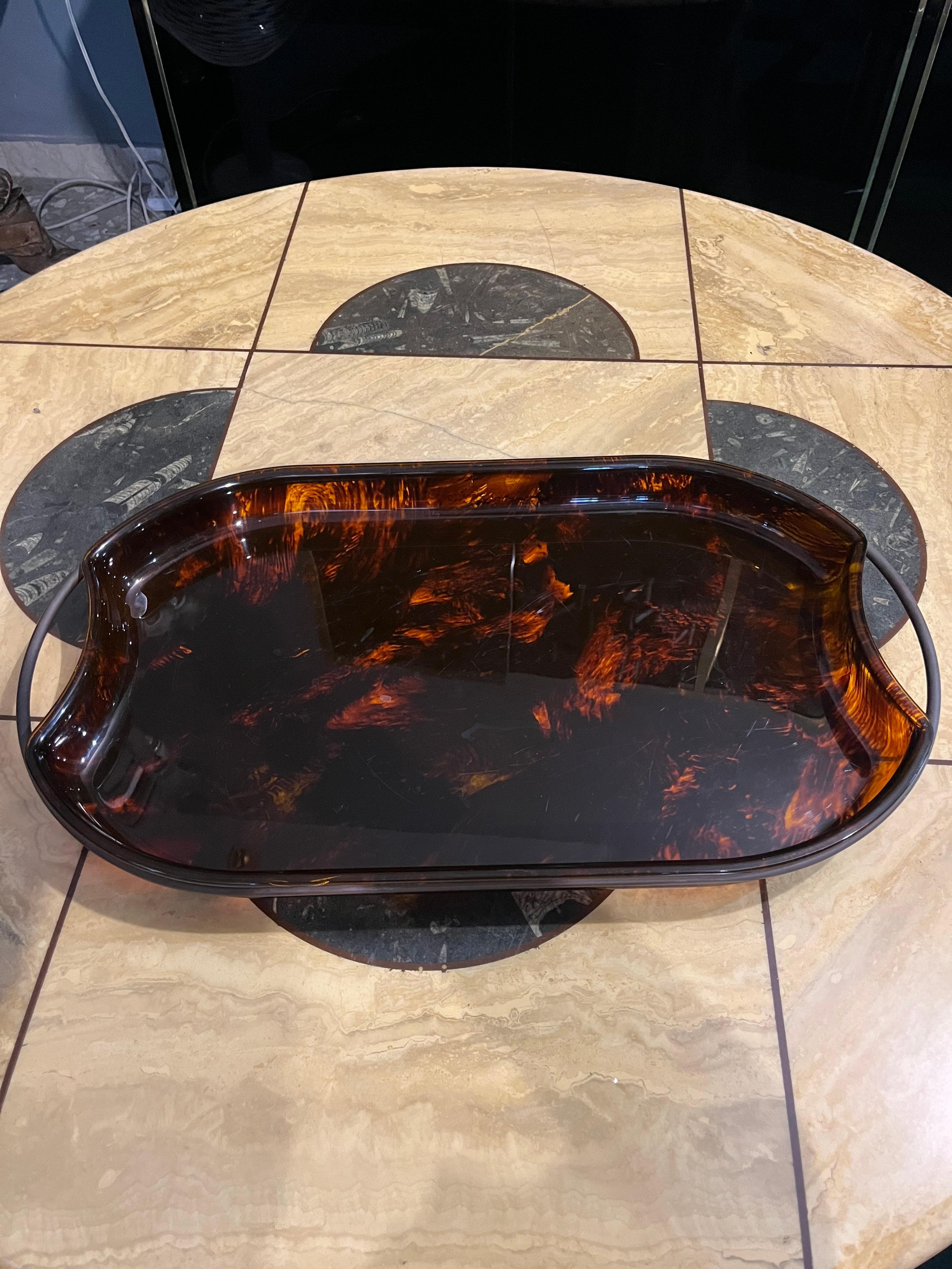 This splendid Guzzini tray is a refined example of 1970s Italian design, an object that combines functionality and aesthetics with a naturalness that only the design of that era can convey. Crafted from tortoiseshell-effect lucite with brass