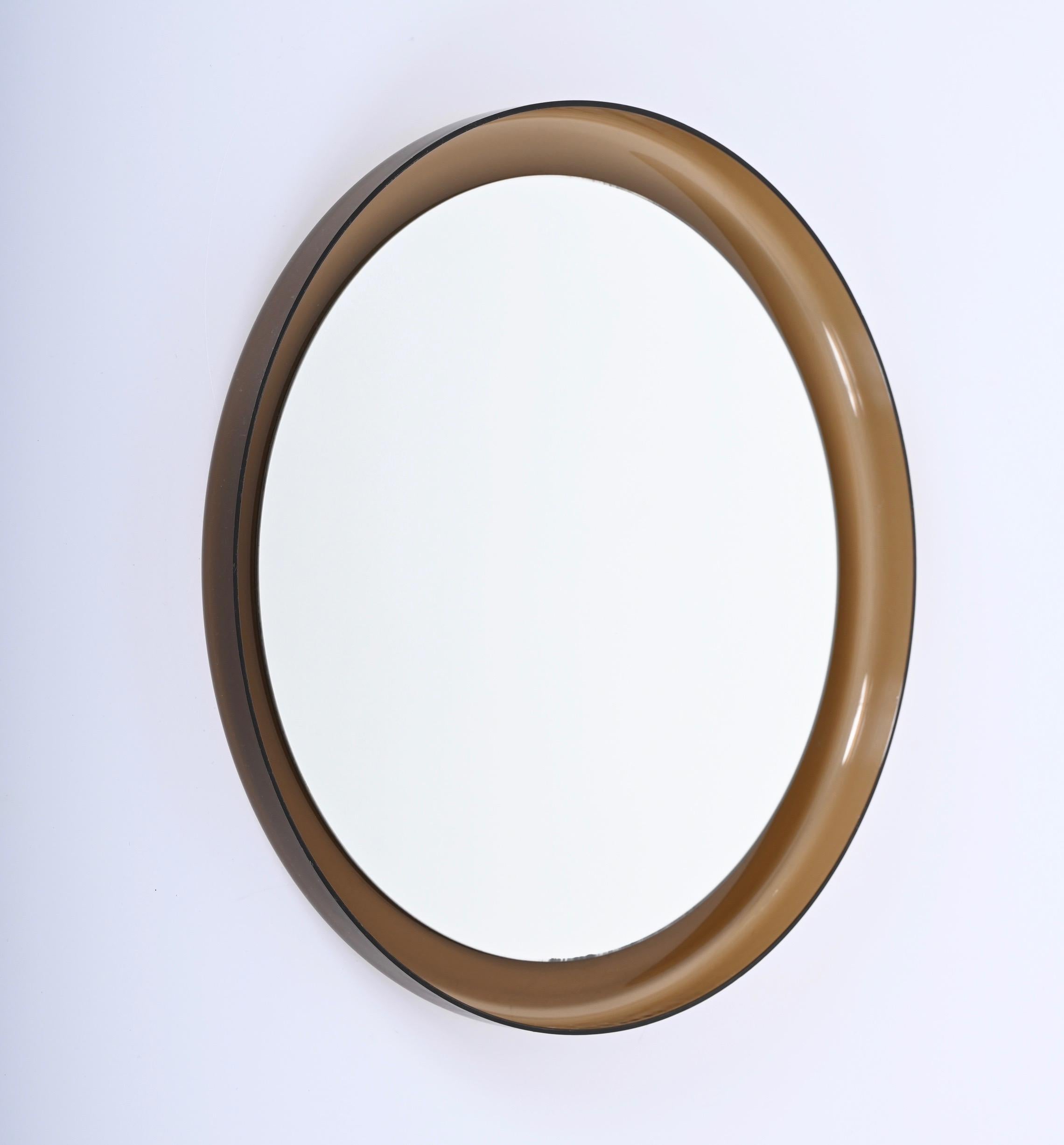 Unique midcentury smoked brown lucite wall and vanity mirror. This incredible Guzzini mirror was made in Italy during the 1960s.

This stunning piece has a beautiful round brown lucite frame aand it deepens the interior mirror. This mirror is in