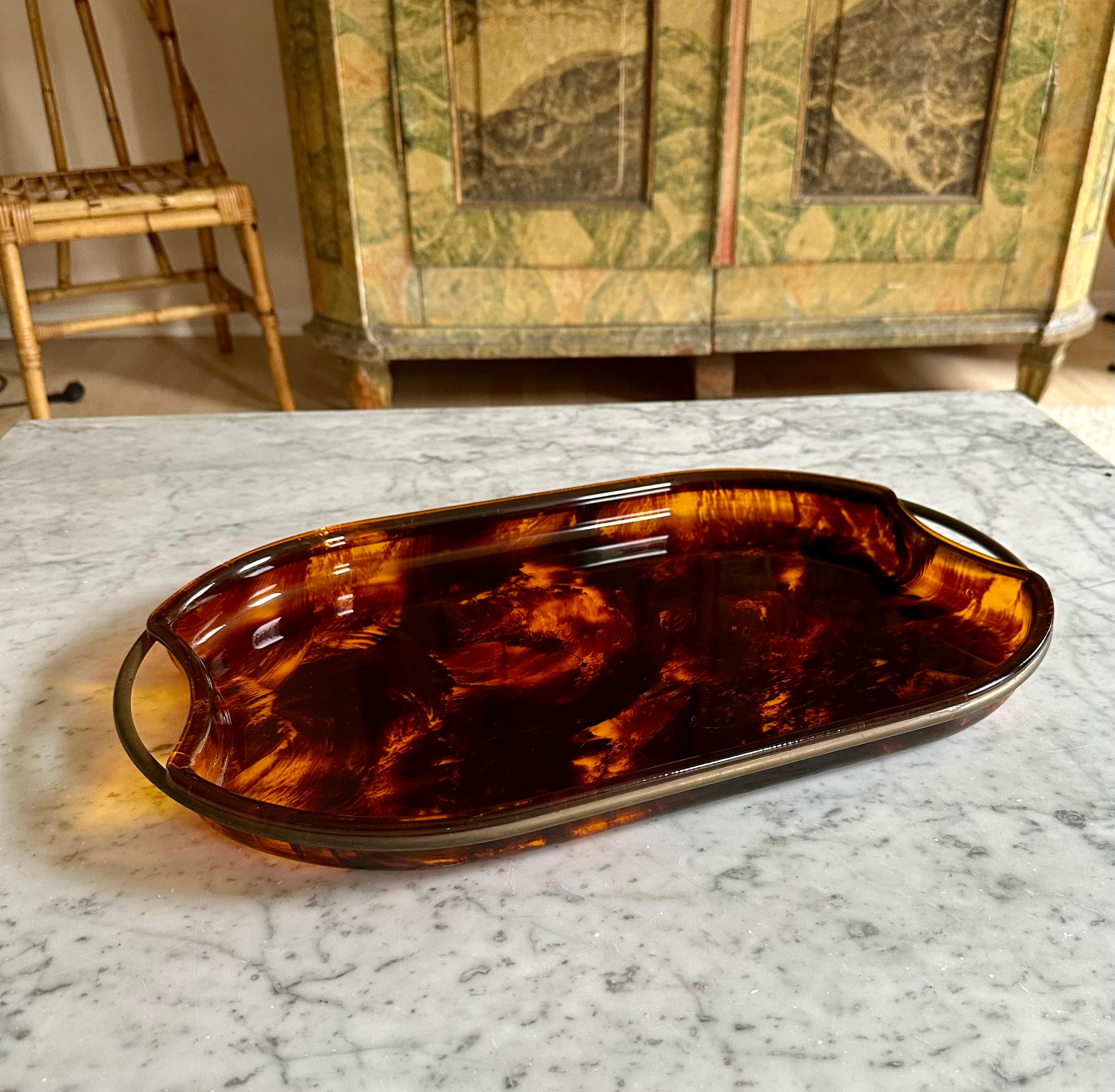 Indulge in the timeless elegance of this midcentury oval serving tray from the illustrious design house, Guzzini, hailing from the artistic landscape of Italy in the 1970s. Crafted with meticulous attention to detail, this exquisite tray seamlessly