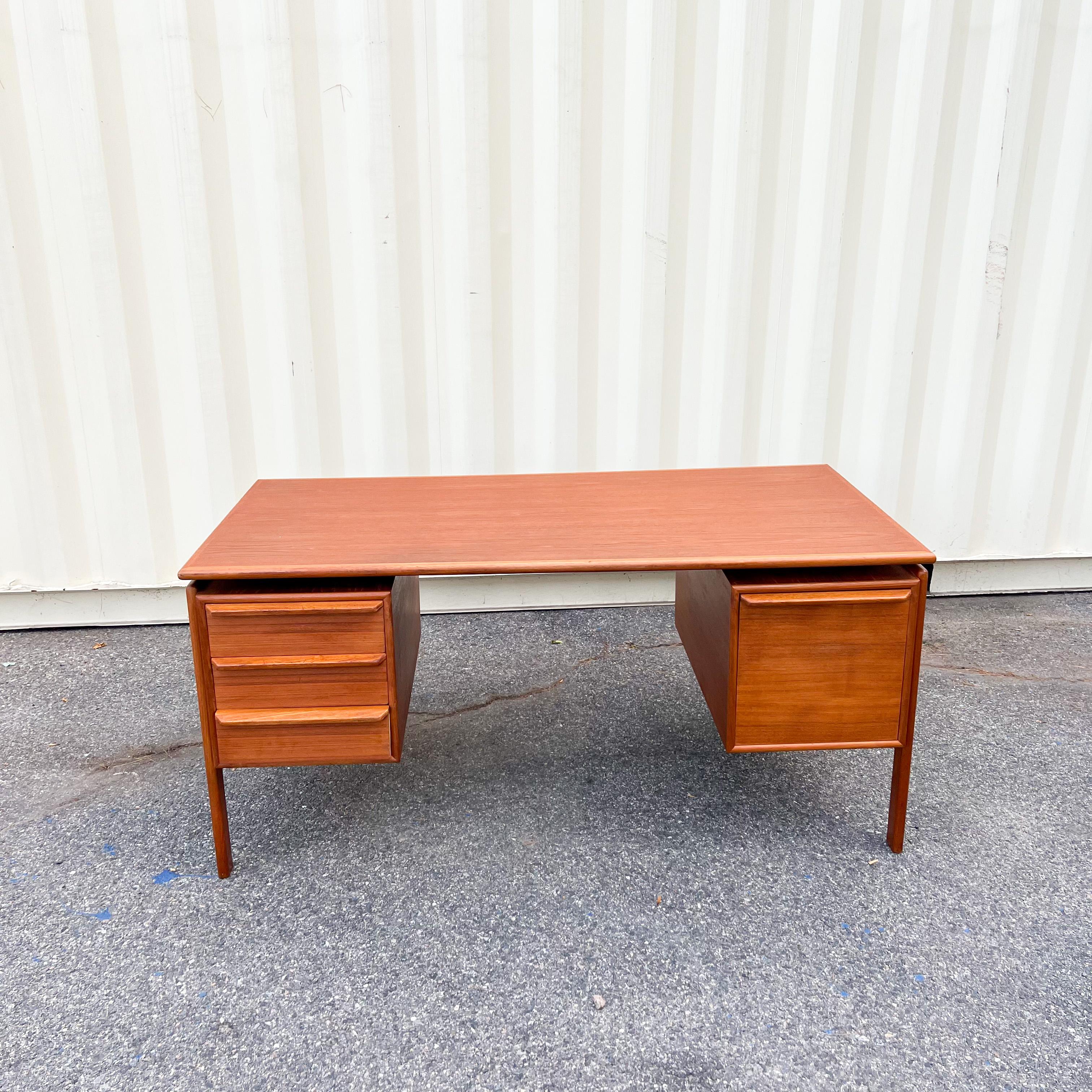 Stunning Danish modern floating top teak desk manufactured by G.V. Møbler in Denmark, circa 1960s. On the left side features three dovetail drawers, and on the right side, it has a wide file drawer with aluminum rails that facilitate the sliding of