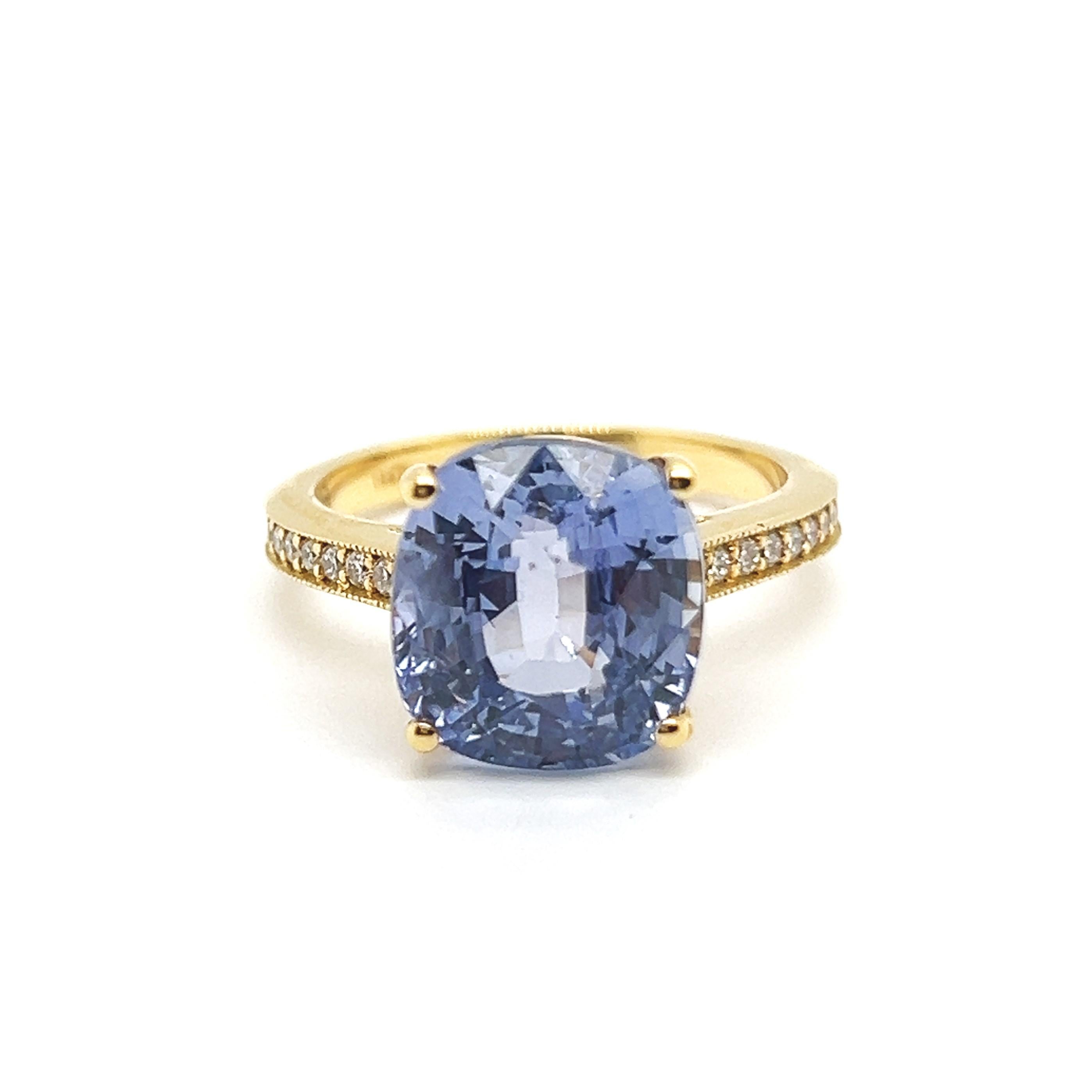 Cette bague exquise, conçue en or jaune 18 carats, présente en son cœur un superbe saphir de 9,41 carats taillé en coussin. Le saphir, vierge de tout traitement, présente une teinte bleu lilas naturellement pure et envoûtante, une rareté qui rend sa