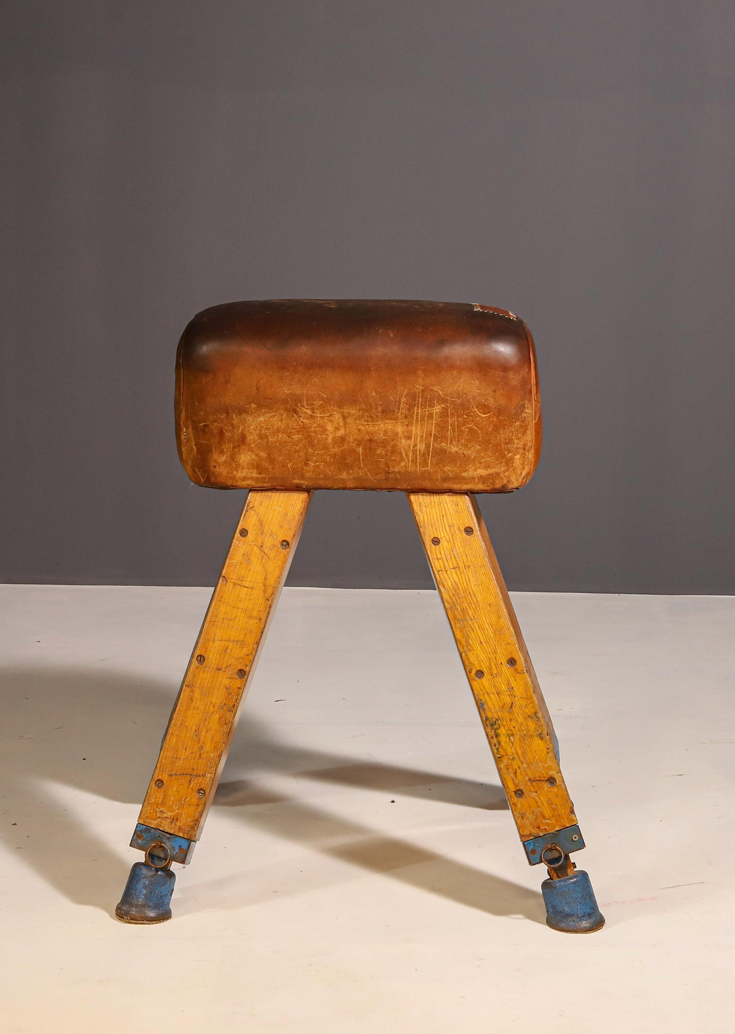 Beautiful early mid-century English gymnastic pommel horse and/or bench vault, made in the former Czechoslovakia in the 1950’s.
This vintage pommel horse features a sturdy oak and iron frame. The seat has aged patinated leather with a few scratches