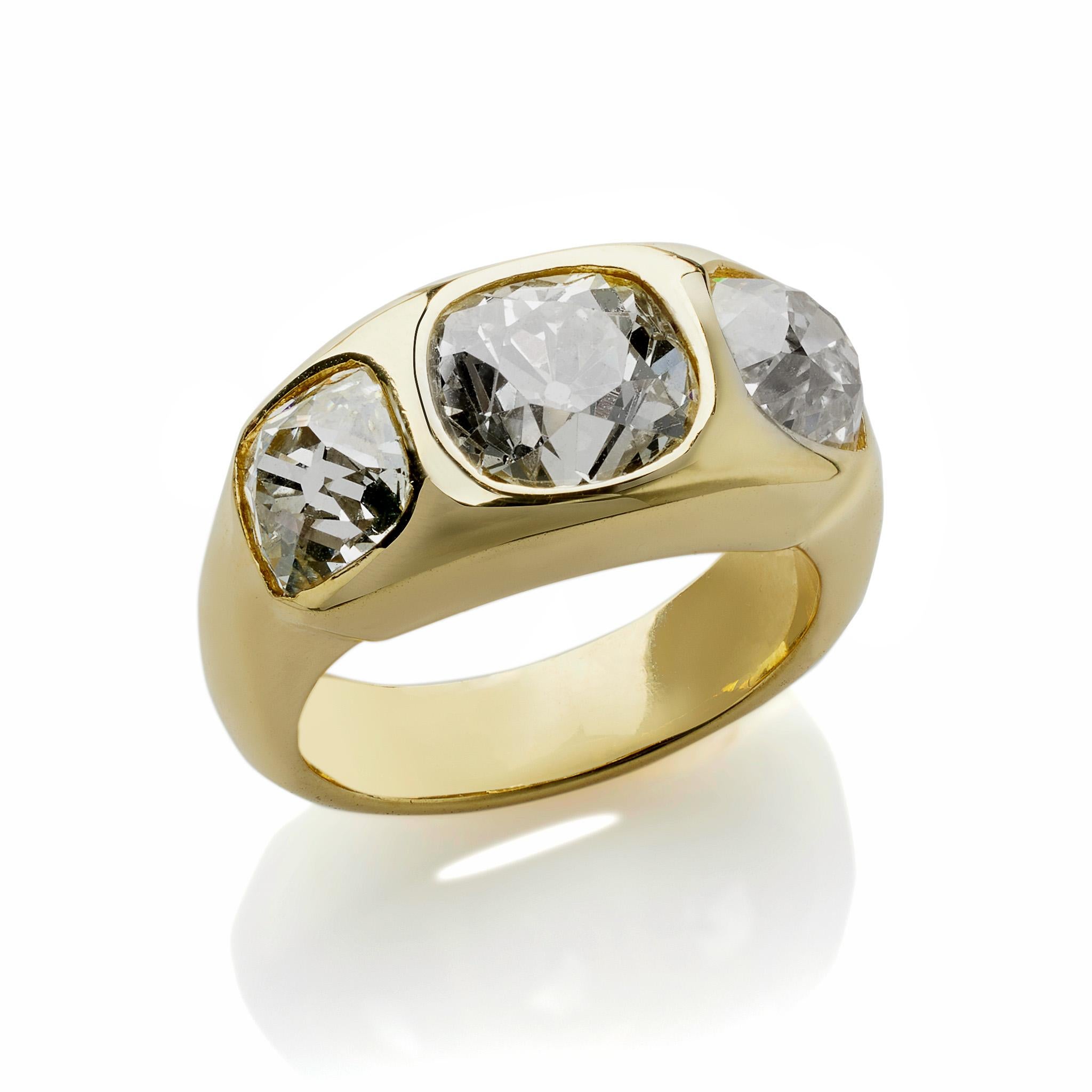 This antique 18K gold, three stone old mine-cut diamond ring dates from circa 1900, and features a central diamond weighing approximately 2.00 carats, flanked by diamonds weighing approximately 1.00 carat each. The central diamond is a