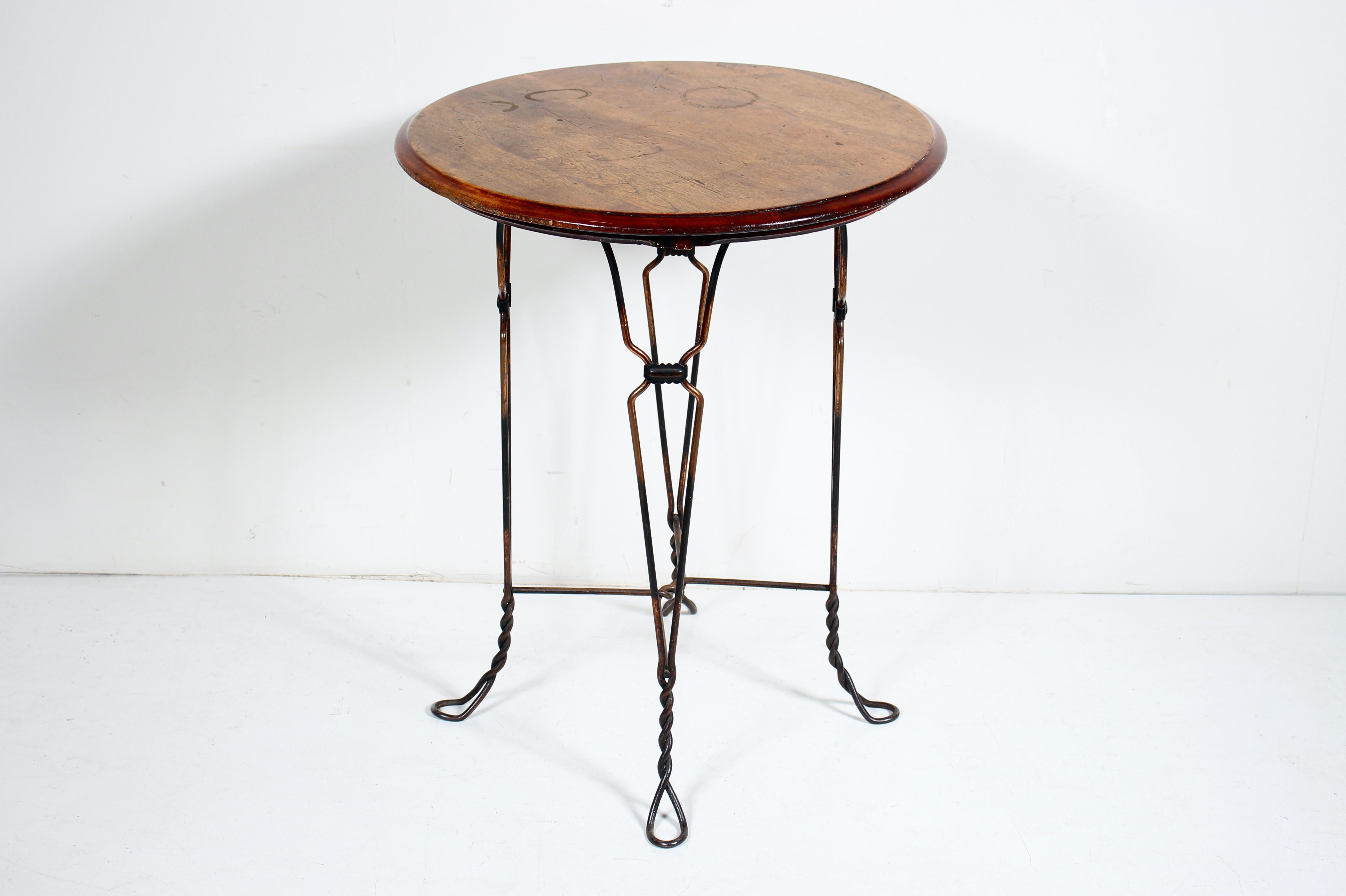 Circa 1900 H. Andrews Japanned Ice Cream Parlor Table.  Cafe Table. Soda Shop Table. Small Kitchen Table. Featuring a clasped and braced Iron framework with solid Quarter Sawn Oak circular surface, atop a four legged curved, and twisted Iron Wire