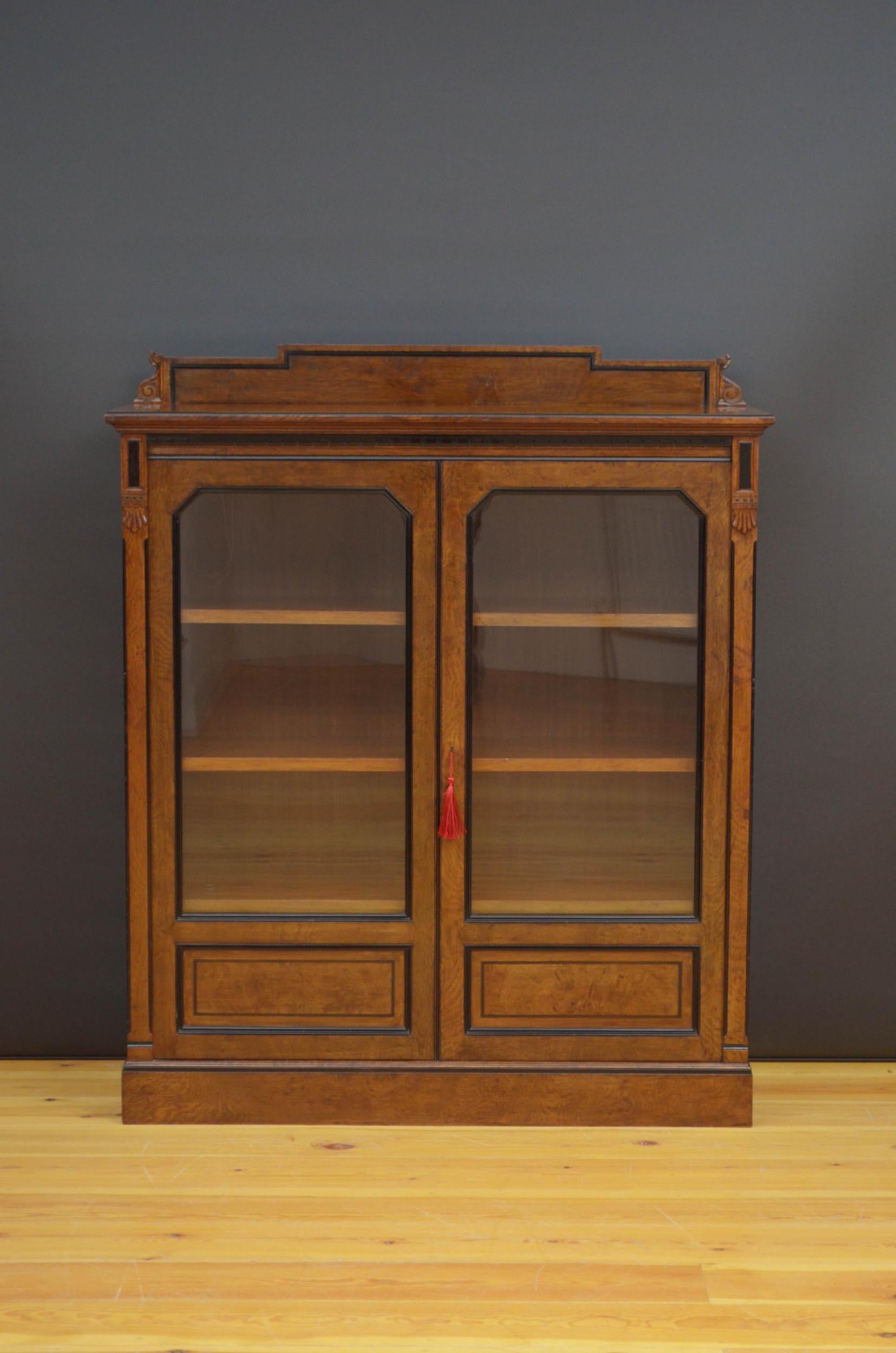 S01 very attractive Victorian glazed bookcase in pollard oak, having carved, shaped and ebonised upstand to the back edge above a moulded top with outstanding pollard oak grain and ebonised dentil carvings above a pair of glazed doors fitted with