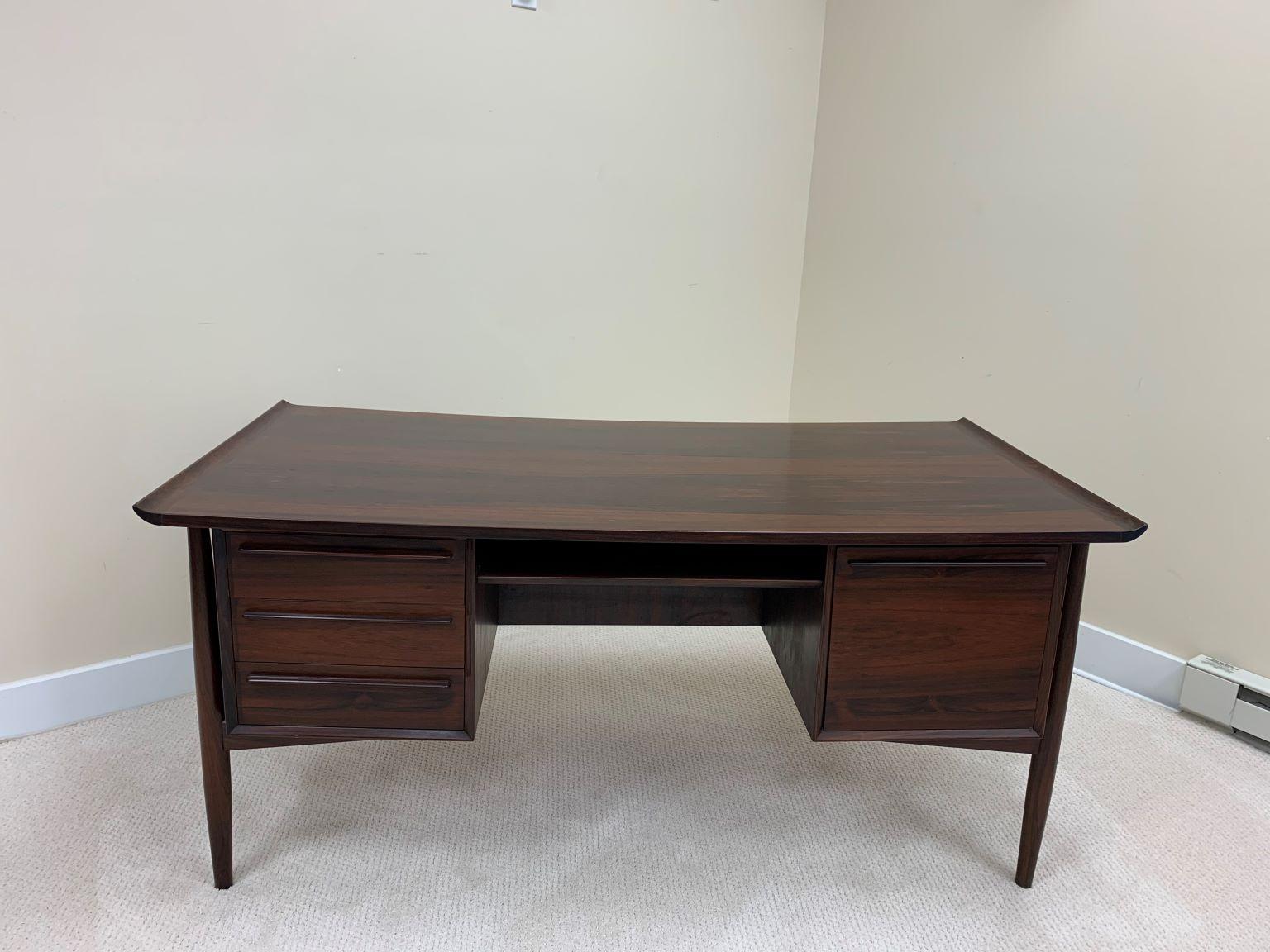 Exceptionally well-crafted rosewood desk by H P Hansen of Denmark features stylish Scandinavian Modern design. Four front drawers and one back compartment for storage as well as a shelf for books. Sculpted rosewood pulls and beautiful original