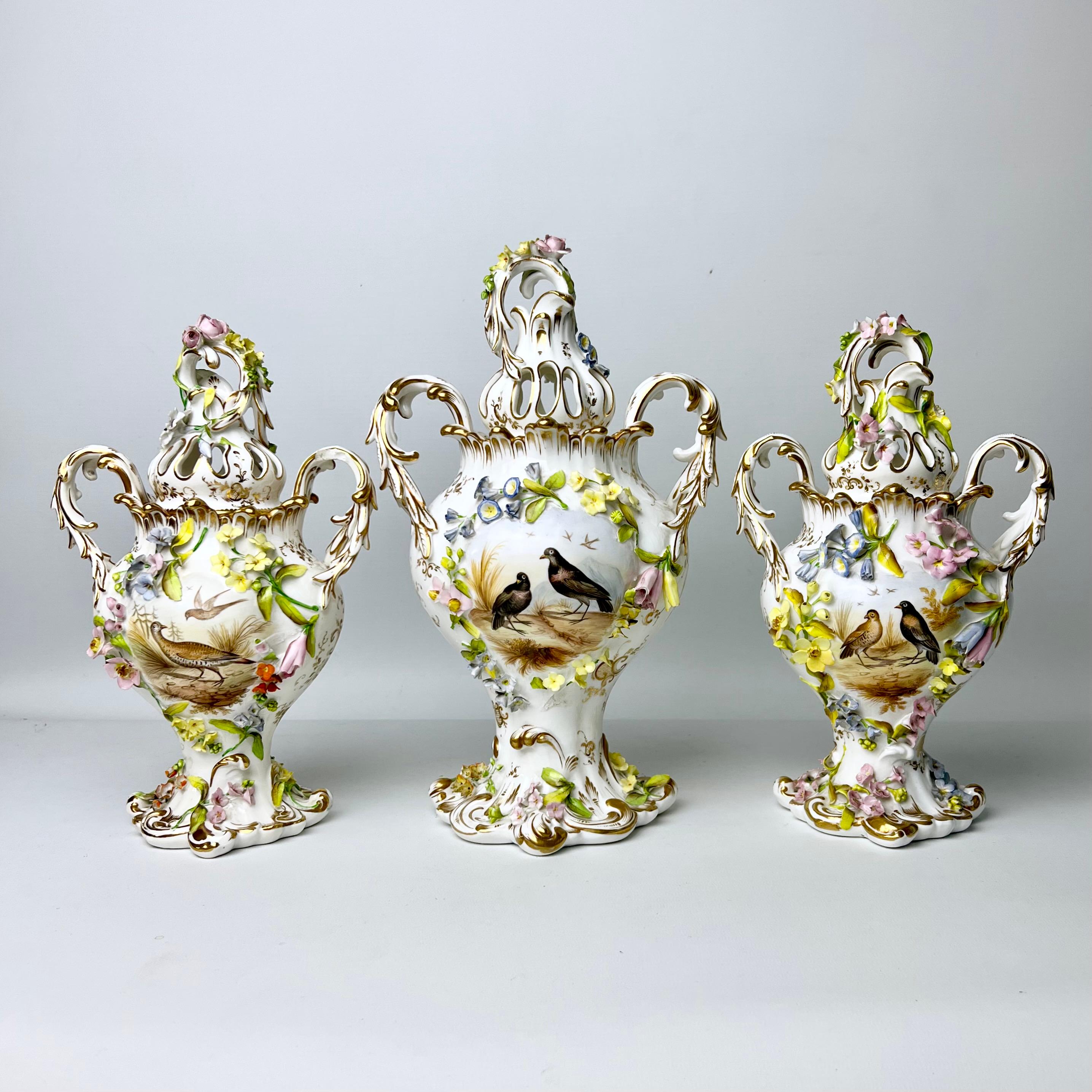On offer is a stunning garniture of three potpourri vases with covers made by H & R Daniel in about 1840. The vases are from the Rococo Revival period, richly decorated with encrusted flowers in the 