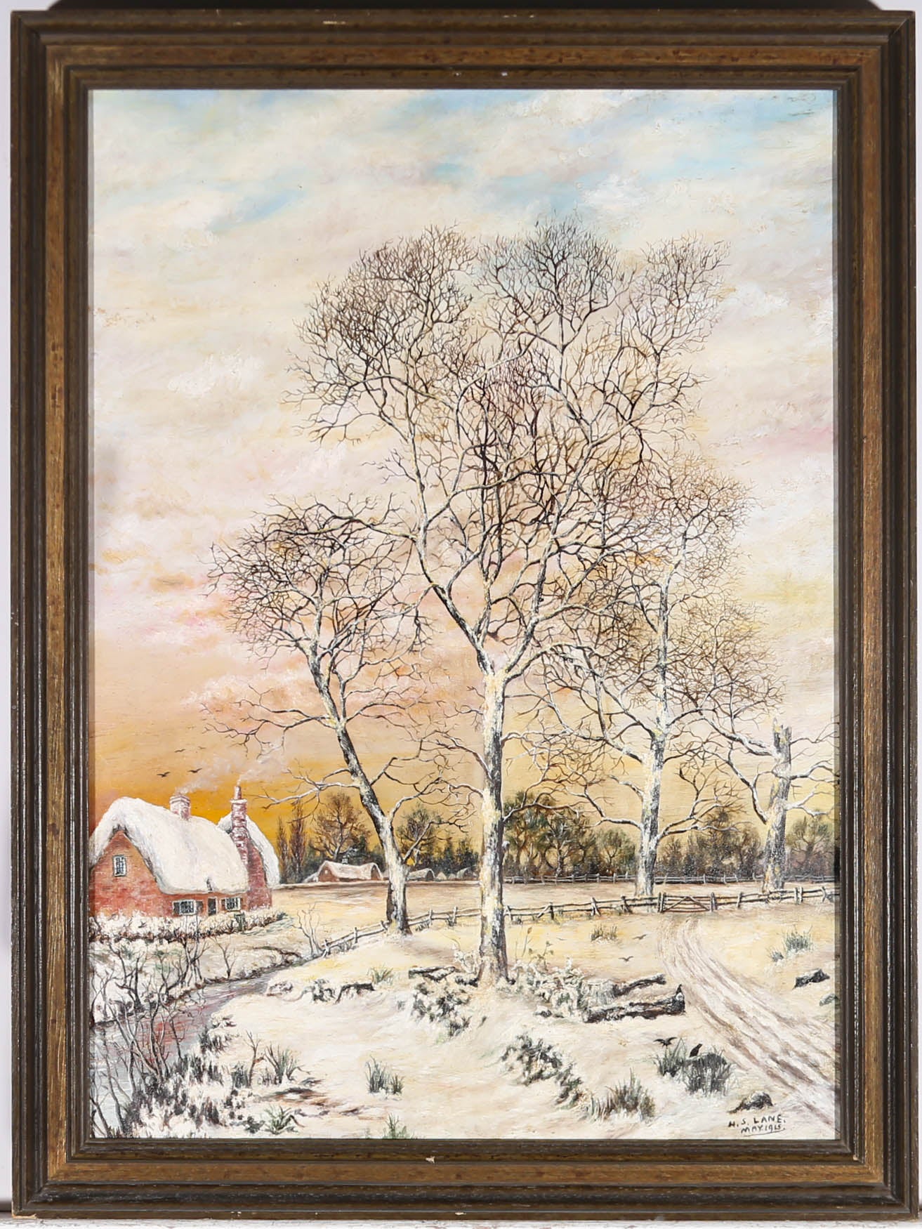 A charming early 20th Century winter scene in oil, showing a thatched cottage, covered in snow, with bare trees in the snowy meadow outside. The artist has signed and dated to the lower right corner and the painting has been presented in a simple