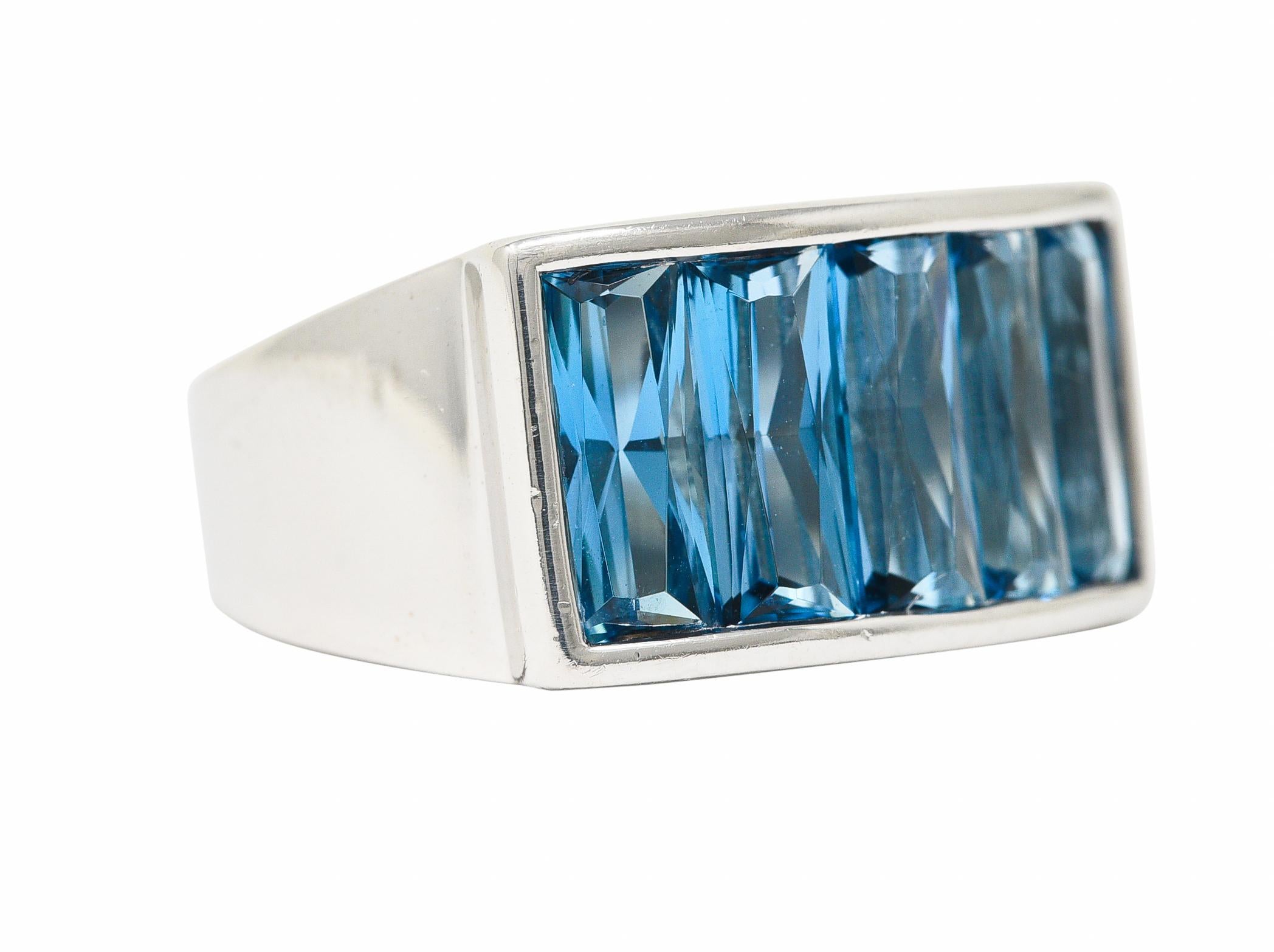 Centering five French cut topazes weighing approximately 5.00 carat total. Transparent bright blue in color with light saturation. Set East to West in a raised channel. With high polish surround and tapered shank. Stamped 750 for 18 karat gold. With