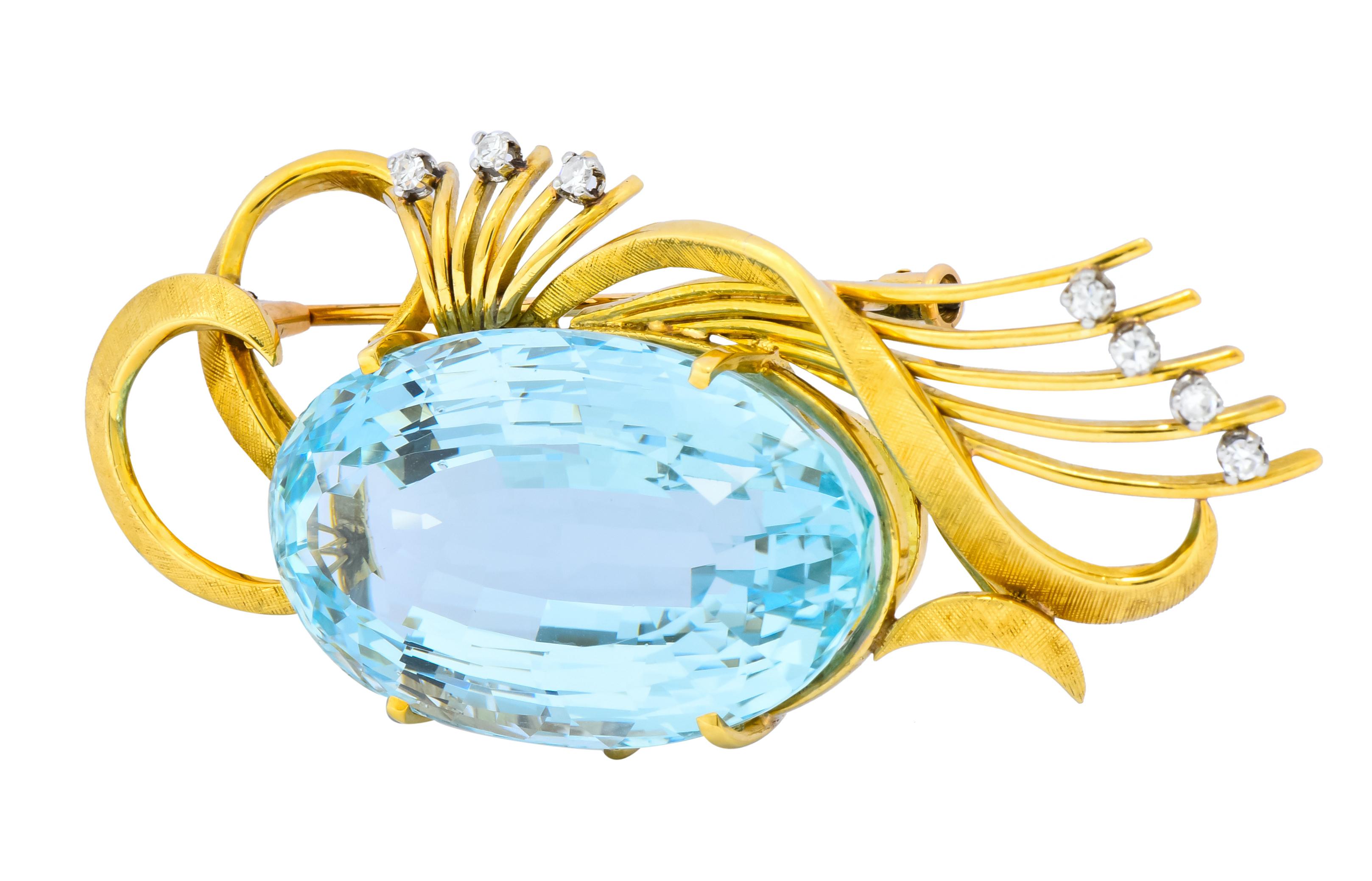 Centering a prong set oval cut aquamarine weighing approximately 55.00 carats, transparent and a vibrant sky blue color

Scrolled and linear gold elements accented by diamonds weighing approximately 0.15 carat total, E/F color and VS