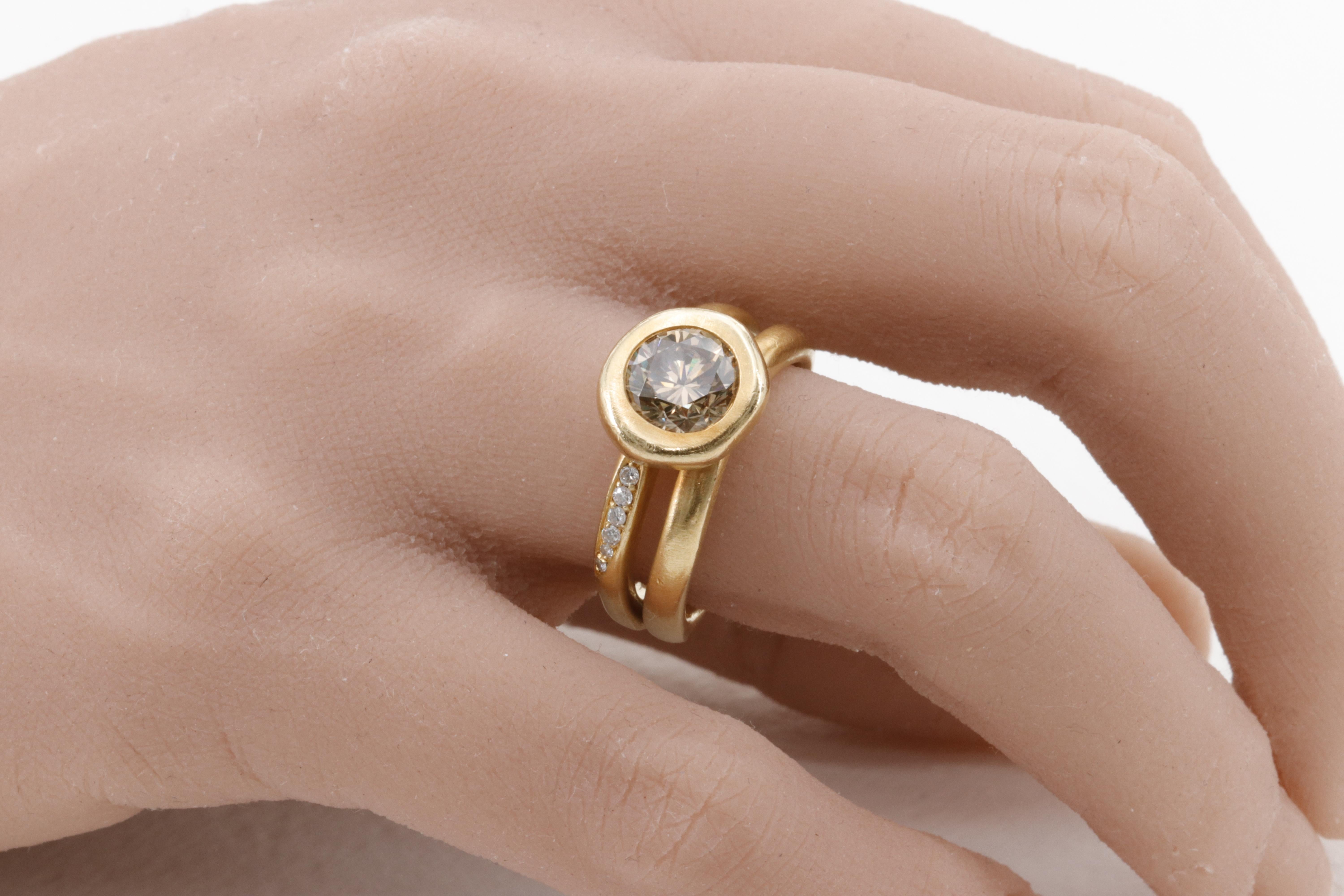 A beautiful statement ring by H. Stern, featuring a warm cognac colored round brilliant cut diamond center stone, bezel set in matte finished 18 karat yellow gold by the master craftsmen at H. Stern. The ring features an additional 6 fine quality