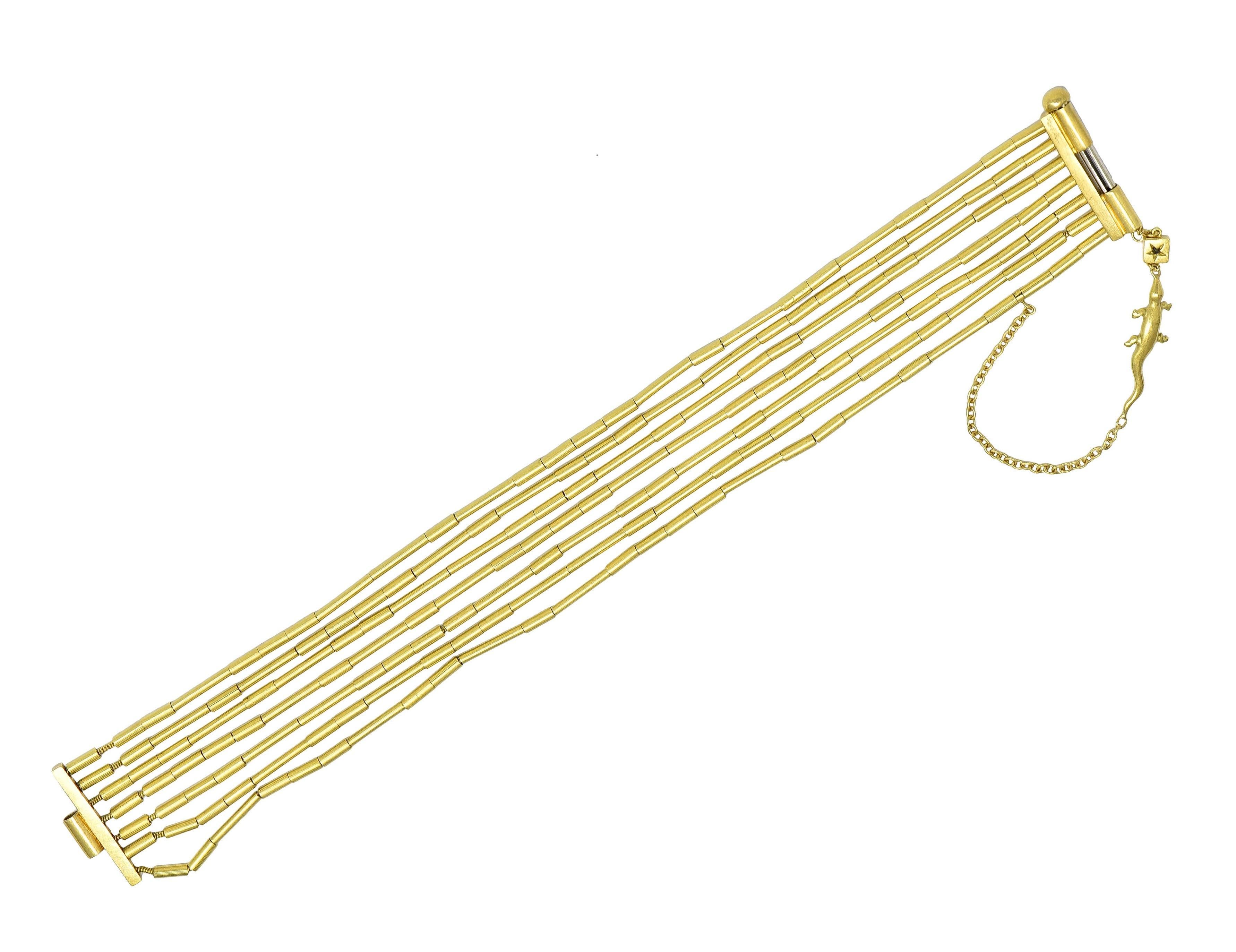 Bestehend aus sieben Strängen goldener Röhrenperlen auf einer goldenen Kette
Hängekette mit goldenem Eidechsen-Charme und Diamant
Prinzessinnenschliff und ein Gewicht von etwa 0,08 Karat
Augenrein und hell - mit Lünette 
Mit Schiebeverschluss