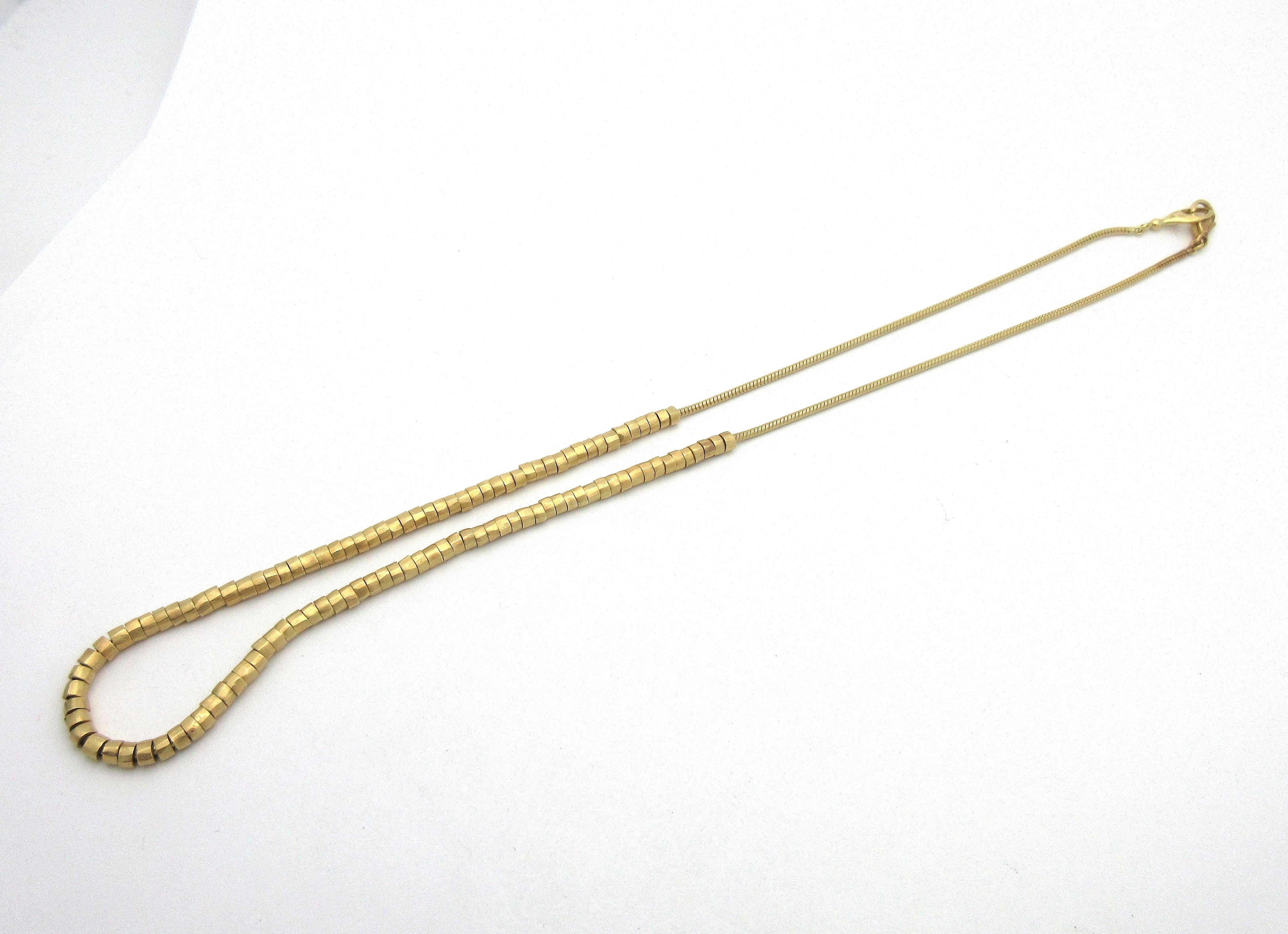 A beautiful authentic H. Stern necklace in solid 18k yellow gold, featuring a smooth snake chain, strung halfway with hammered gold beads.  The necklace measures approximately 17