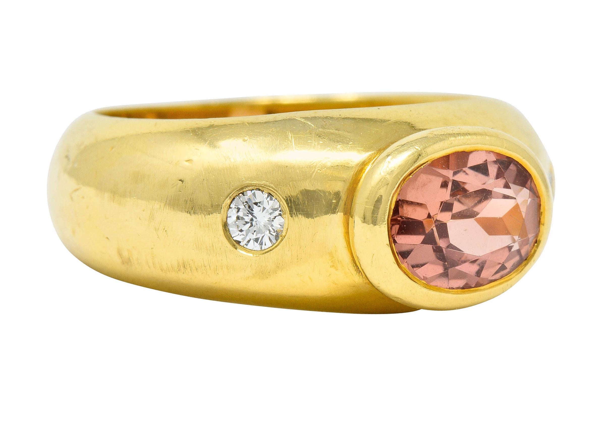 Wide band ring centers a bezel set oval cut imperial topaz

Transparent with uniform peachy-orange color

Flanked by two flush set round brilliant cut diamonds

Weighing in total approximately 0.20 carat with F/G color and VS clarity

Stamped 750