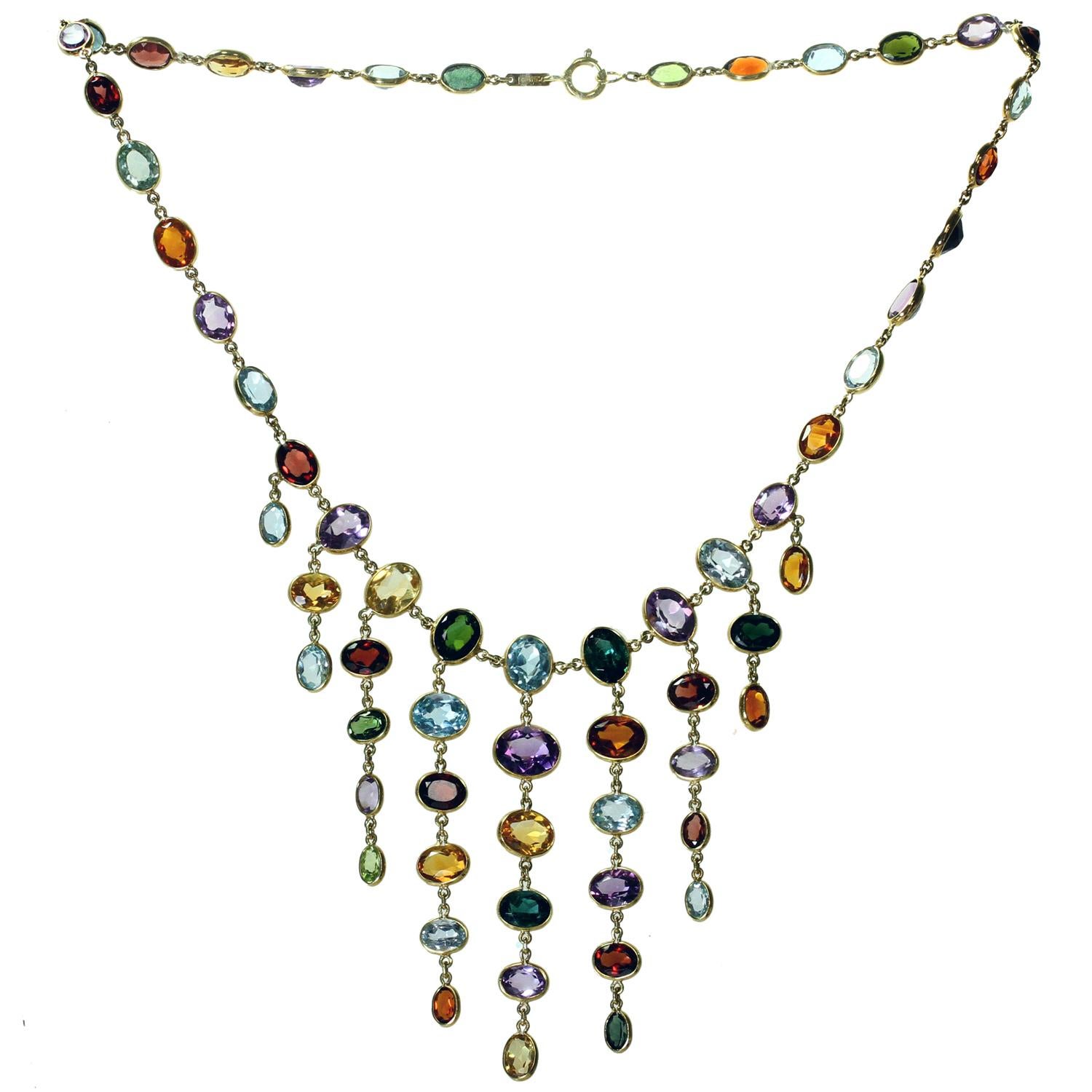 This exquisite H. Stern chandelier necklace is crafted in 18k yellow gold and set with a vibrant multi-colored array of faceted oval gemstones: aquamarine, garnet, peridot, blue topaz, amethyst, citrine, and tourmaline. Made in Brazil circa 1980s.