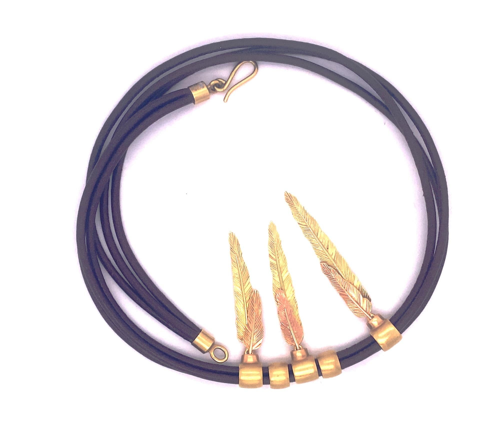 This is a stunning necklace by H. Stern from the Purangow collection inspired by Amazon tribes.  The necklace has a design with two color gold feathers layered on top of each with attached to a three strand leather necklace with gold clasp. Signed