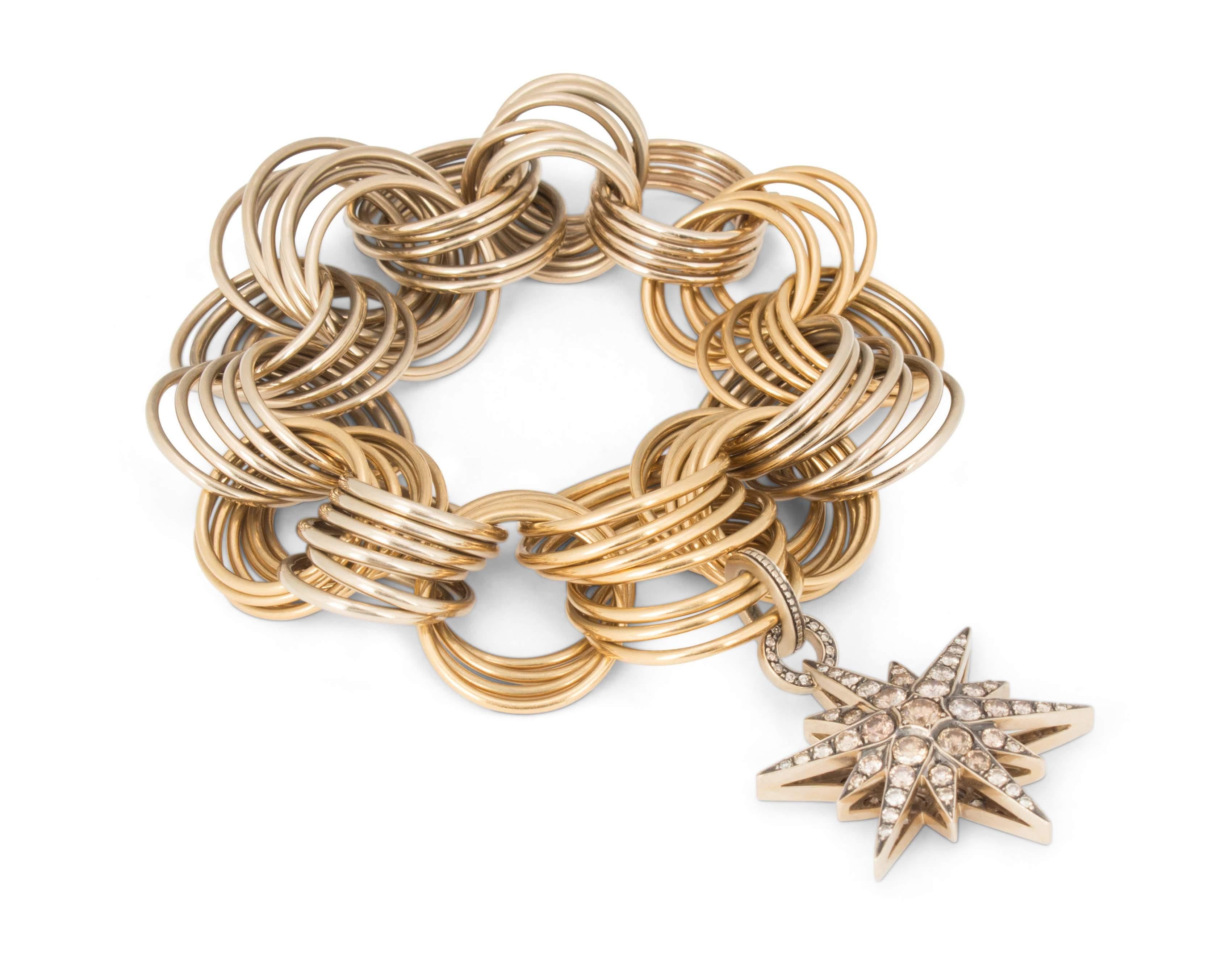 Authentic H. Stern bracelet comprised of a series of interlocking rings crafted in two-tone 18 karat gold. H. Stern's 'Star Collection' charm completes the bracelet. The charm is crafted in 18 karat blackened gold and set with an estimated 5.00