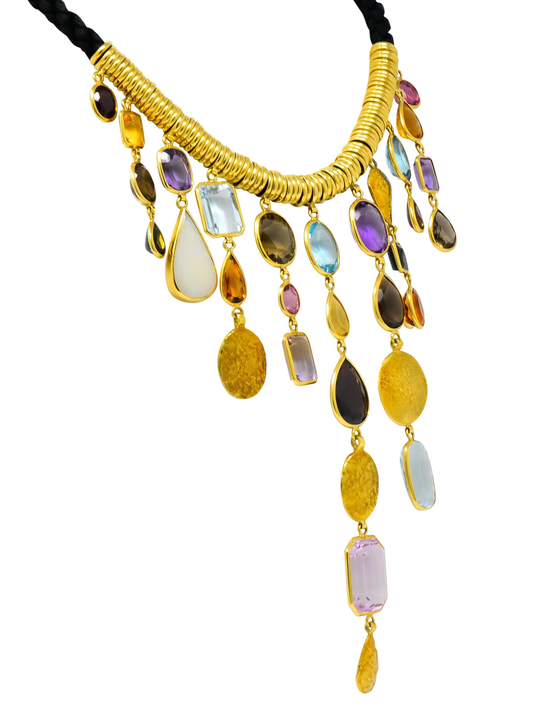 Designed as a woven cord necklace set to the front with gold roundels and eleven graduated drops

Drops are bezel set with various colored and shaped gemstones with textured gold accents

Featuring opal, garnet, citrine, amethyst, ametrine, smokey