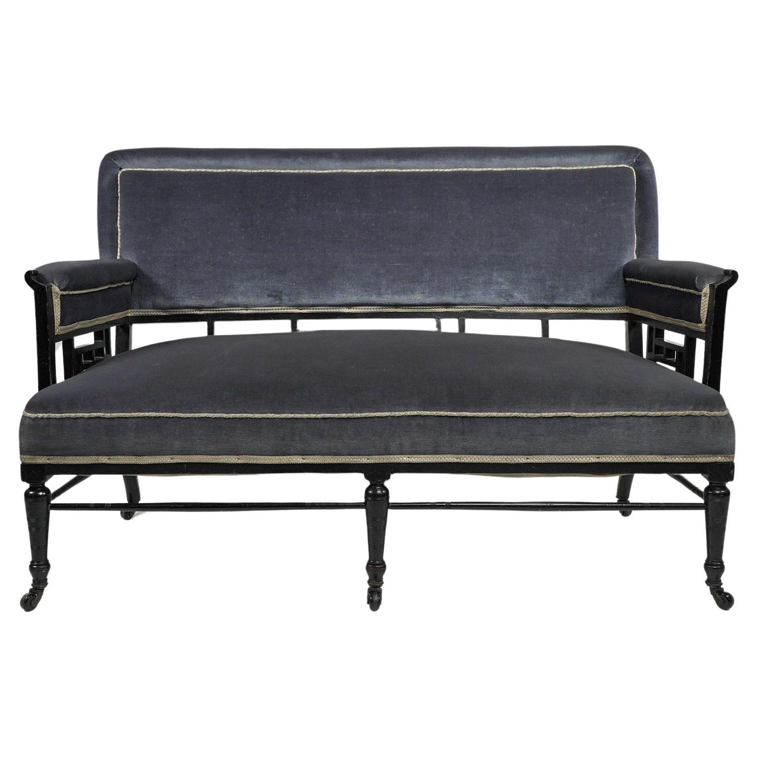 H W Batley attributed. An Anglo-Japanese settee with Japanese fretwork below the backrest and the arms, the arms with pagoda shaped details. Blue velvet upholstery, slightly faded but in good condition, standing on turned legs united by finely