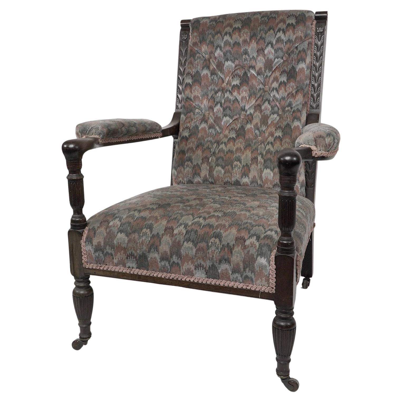 Henry William Batley (attributed) Jas. Shoolbred., a mahogany armchair, with stylised floral carved details to the back supports, the curved arms with elbow pads on fluted supports, and fluted legs on castors.