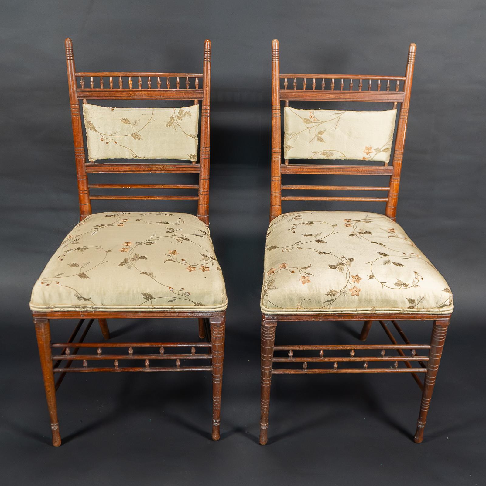 H. W. Batley for Collinson & Lock
A fine pair of Aesthetic Movement side chairs. With extended turned and incised finials, an upper turned gallery above the professionally re-upholstered padded backrests, and seats in an Aesthetic style floral