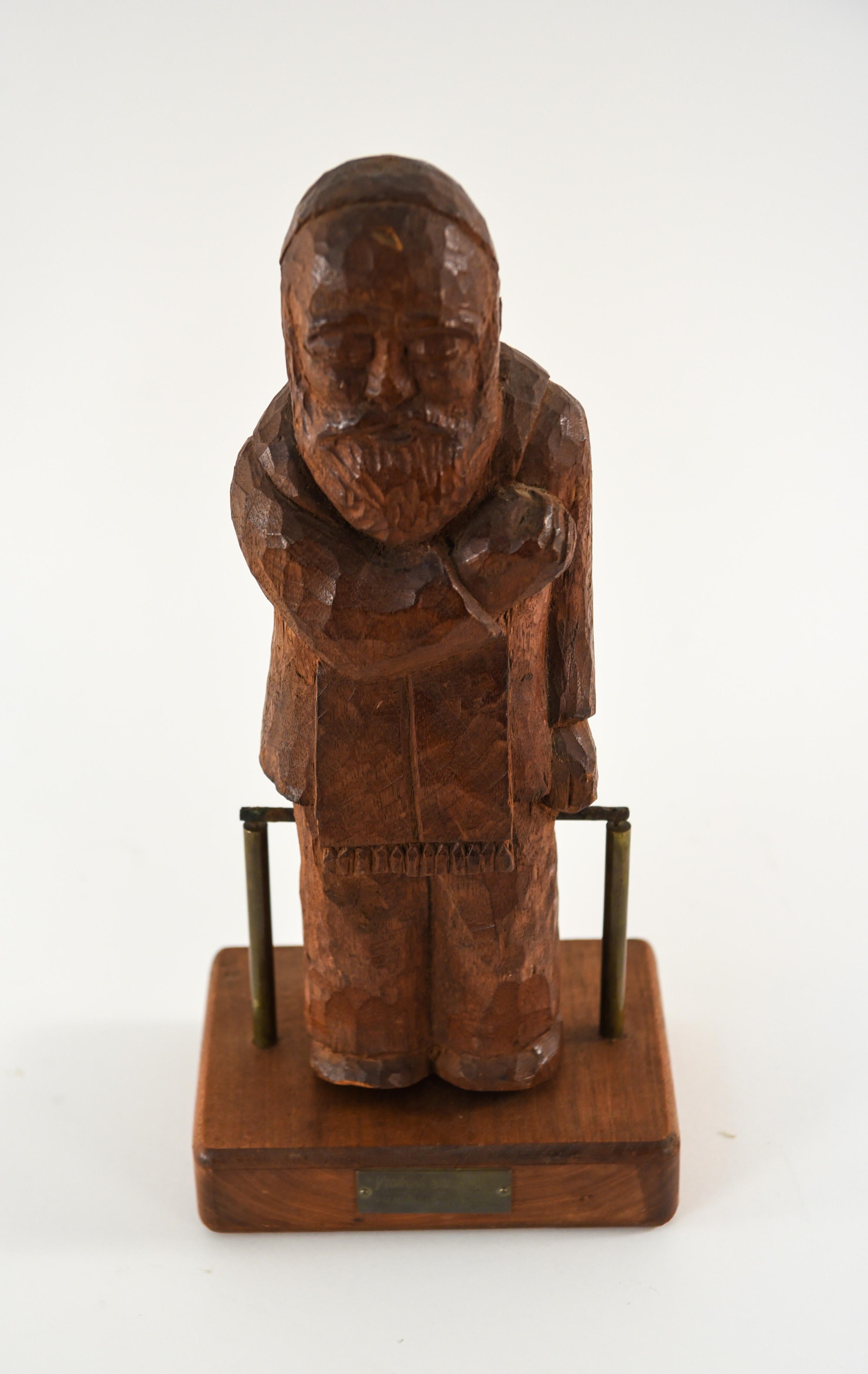 A Kinetic bobbing wooden sculpture of a Rabbi figure. With a small metal plaque adorning the front of the base.