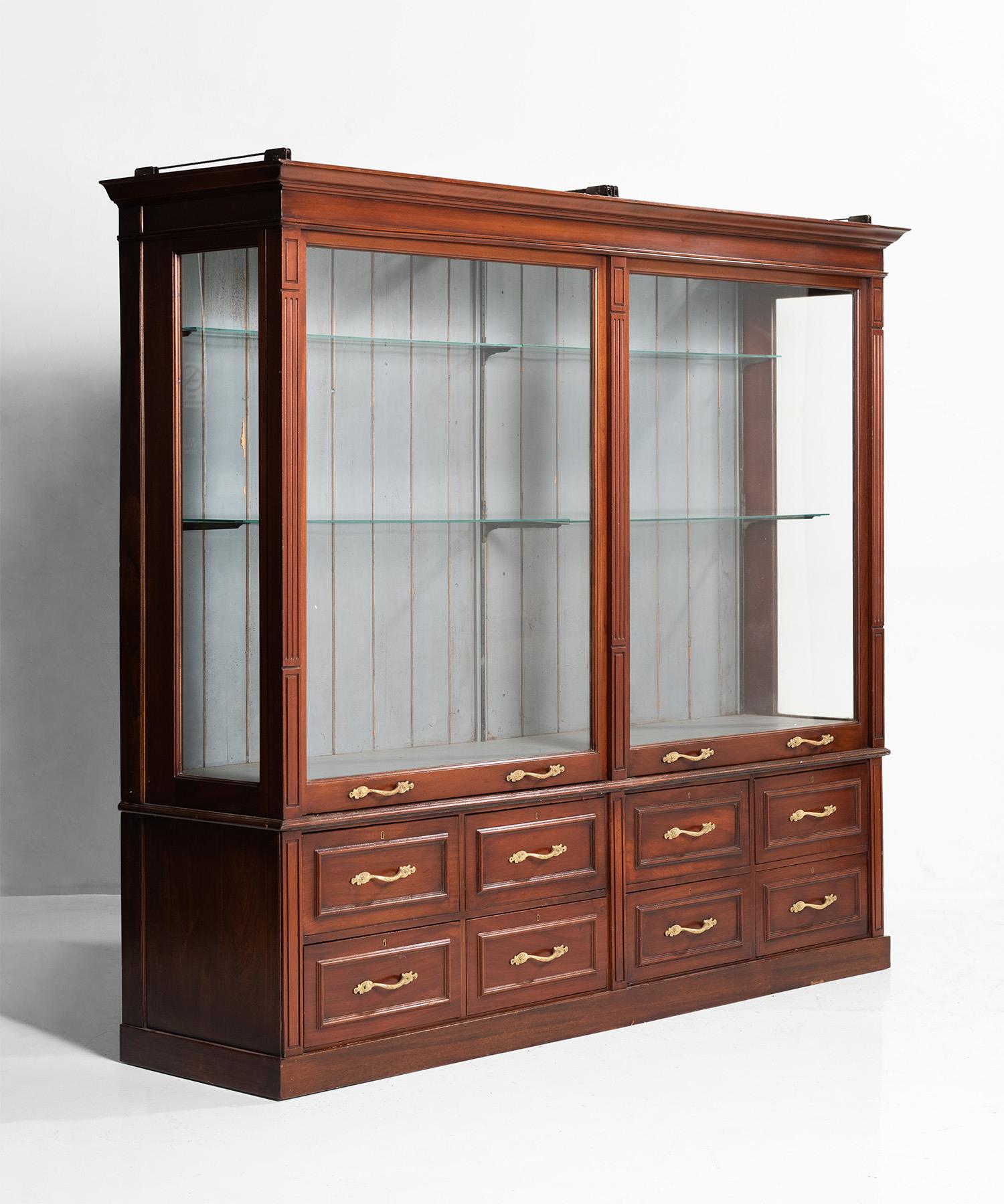 Shop fitting display cabinet built with mahogany. Vertical sliding glass doors designed with weighted counterbalance.
 