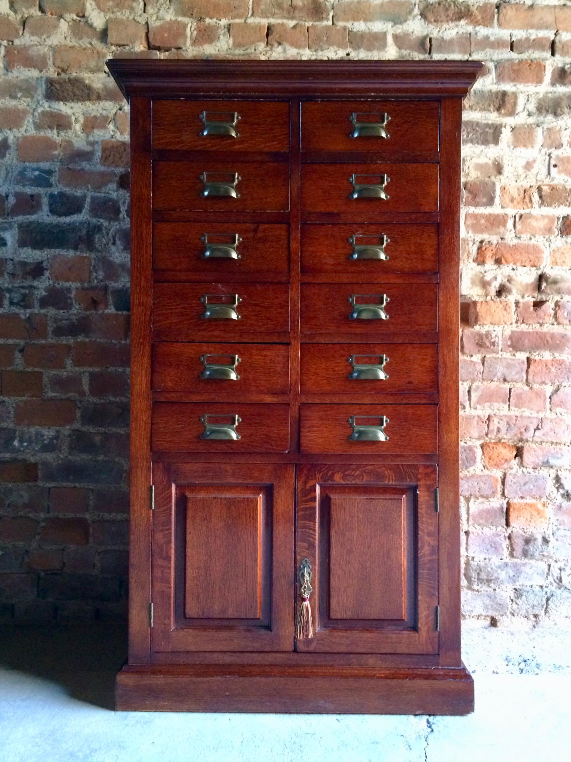 A fabulous early 20th century oak collectors cabinet, circa 1900s, rectangular top over twelve drawers above a pair of panelled cupboard doors all with original brass cup handles and raised on a plinth base. 

CONDITION REPORT: 
The cabinet is in