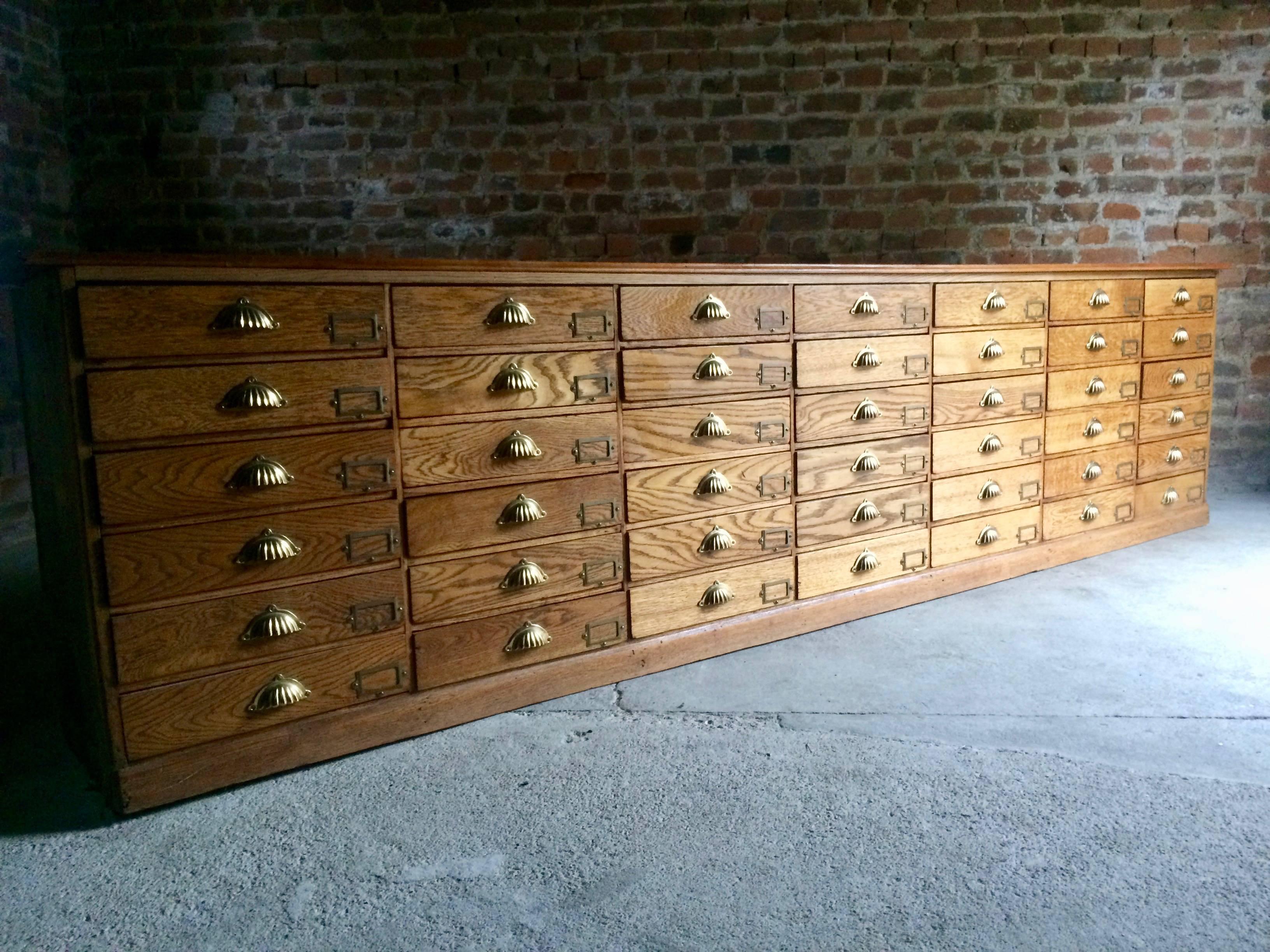 Magnificent antique 19th century Haberdashery Golden oak shop counter chest of 42 drawers circa 1875 from the Victorian era, the rectangular lift off counter top over forty two pull-out drawers all with brass shell cup handles and brass index card