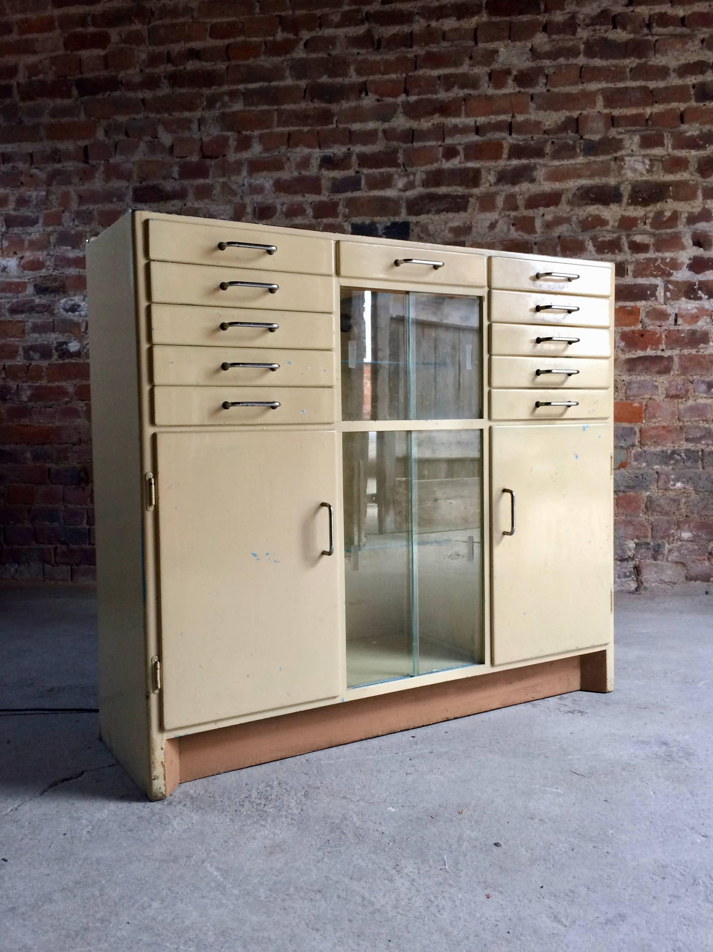 A fabulous early 20th century Edward Doherty & Son, Edmonton, London, Dentist's cabinet, circa 1930s, the primrose colored cabinet with its black rectangular top over nine pull out drawers above two cupboards each with a single shelf, two glazed