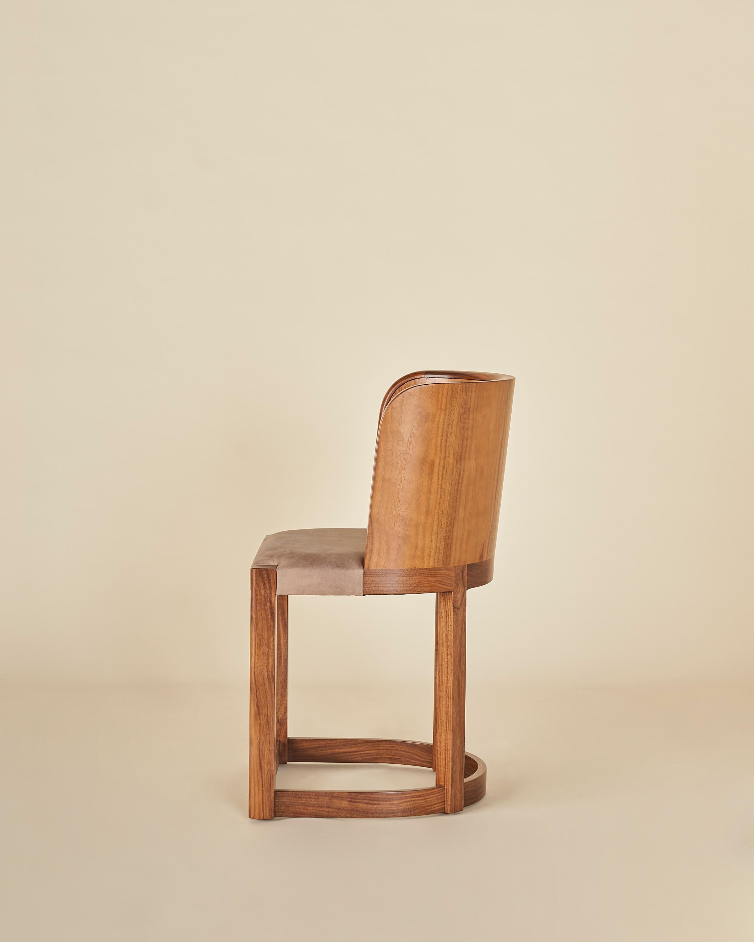 Beautiful walnut dining chair with a molded solid wood back with a tight pecan leather seat.

Our collection pays homage to the everlasting idea of home, a place that is alive as its own character in the story. Taking a reductionist approach to