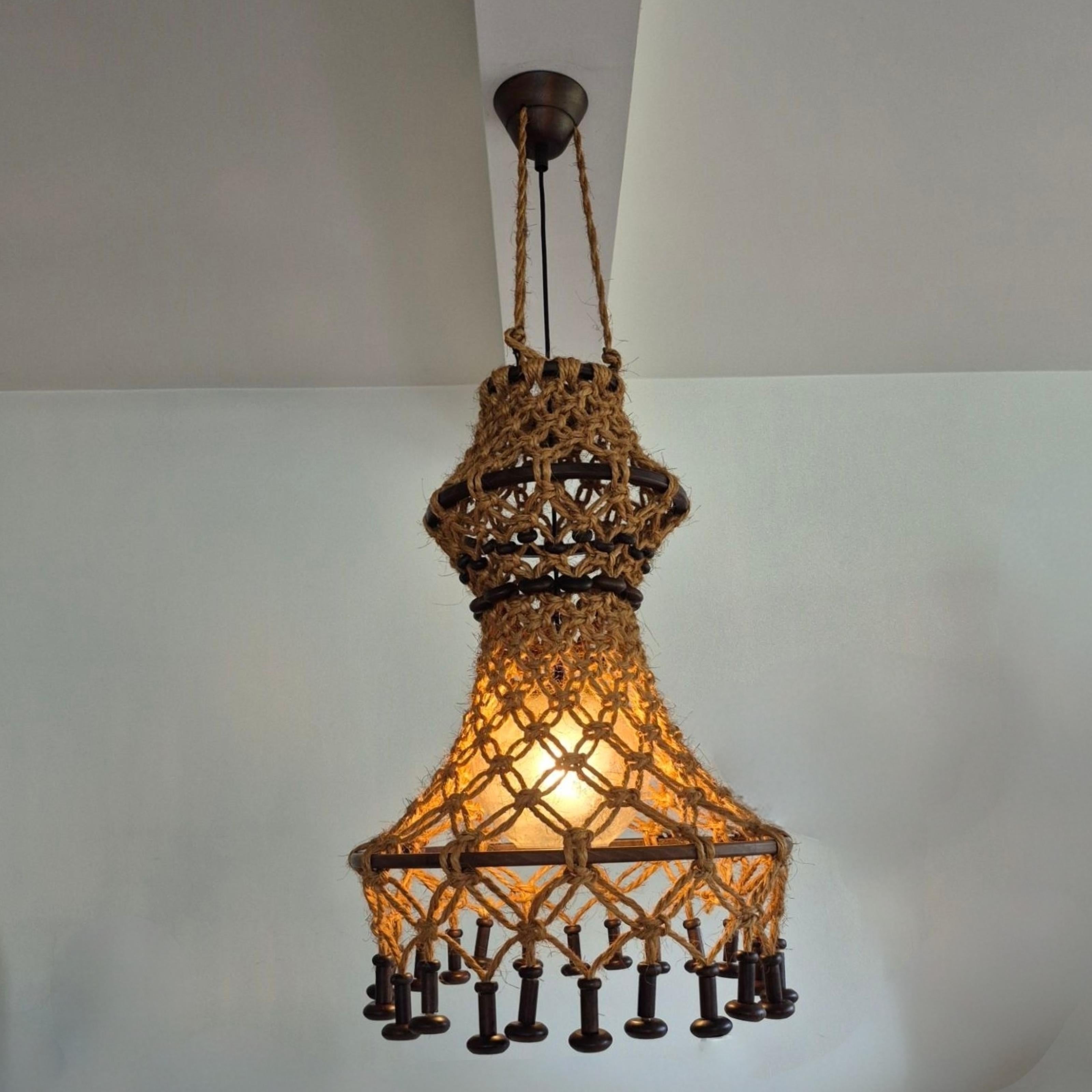 This large wabi sabi macrame pendant lamp was manufactured by Swiss company Temde in the 1960s.
Hand crafted shade made from natural fiber rope knotted around solid hardwood hoops and decorated with solid hardwood beads.
Inside the macrame shade, a