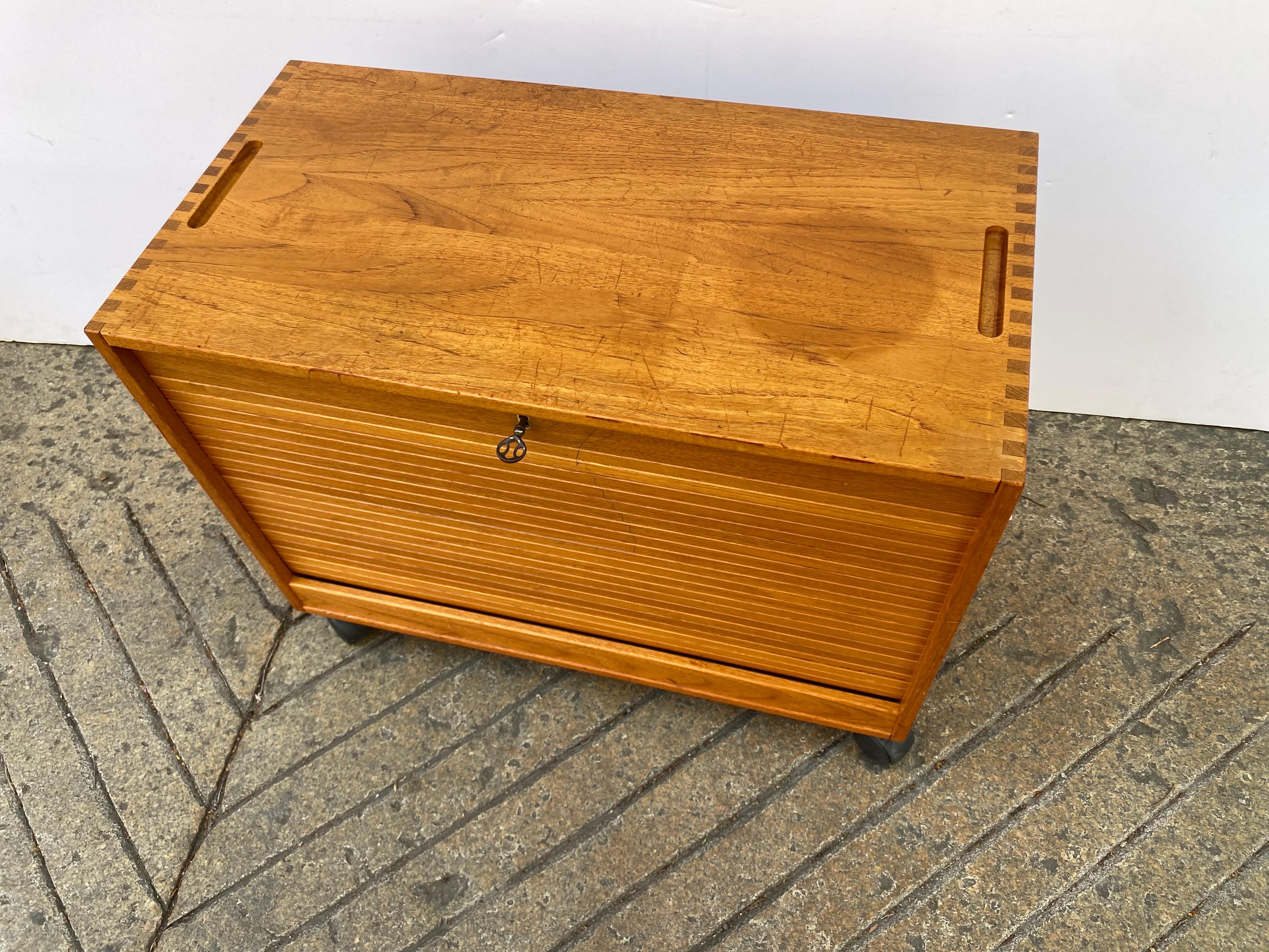 Hadsten Solid Teak Rolling File Cabinet. Tambour Door slides down to reveal a pull out hanging file. Left side open for additional storage. Shows signs of use and wear, but solid teak is not your typical construction.