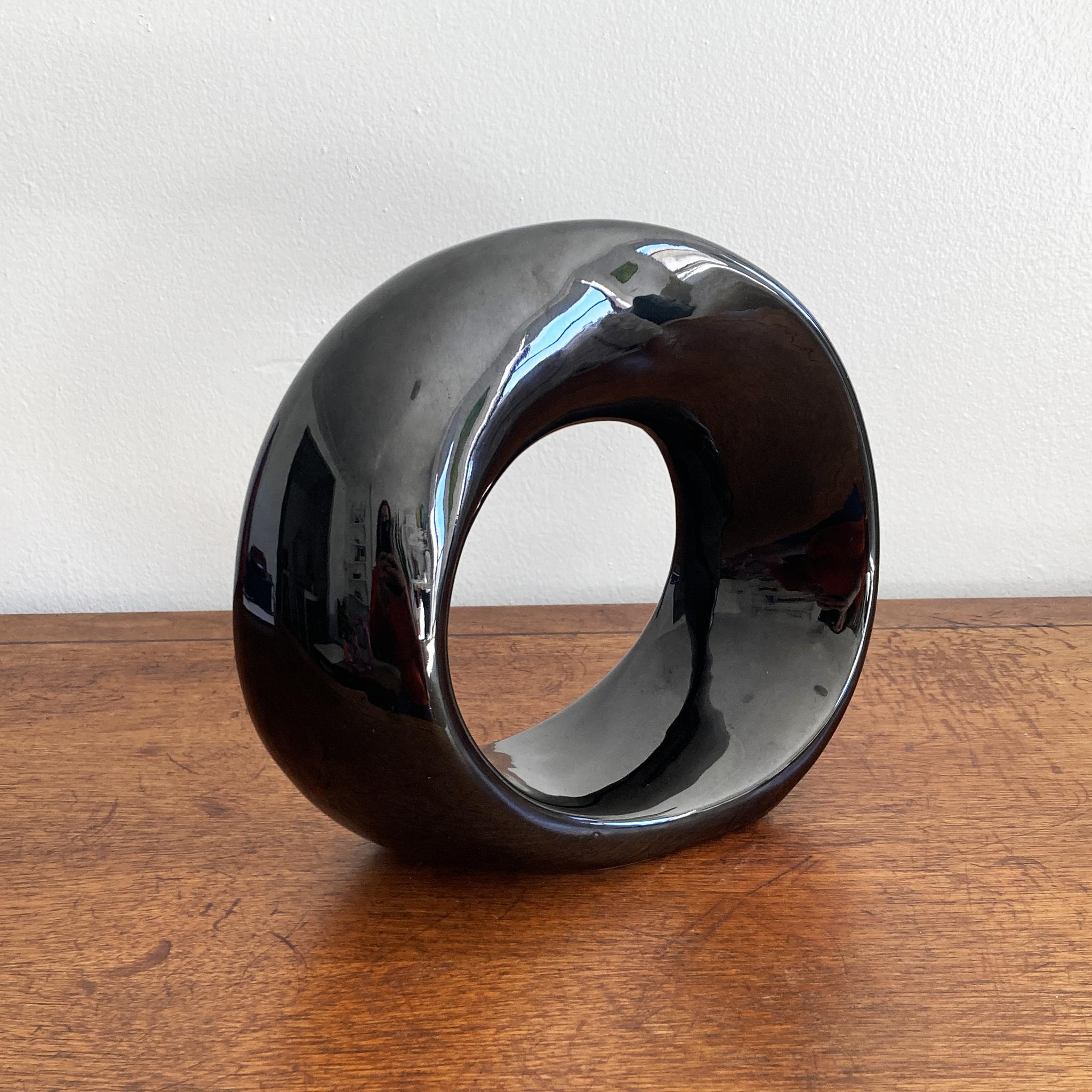 A stunning rare abstract Haeger gloss black ceramic twisted orb sculpture. This piece solicits interest from all angles, the twisted orb silhouette catches the light beautifully. Wonderful on its own, or paired with tonal pieces to form a group. In