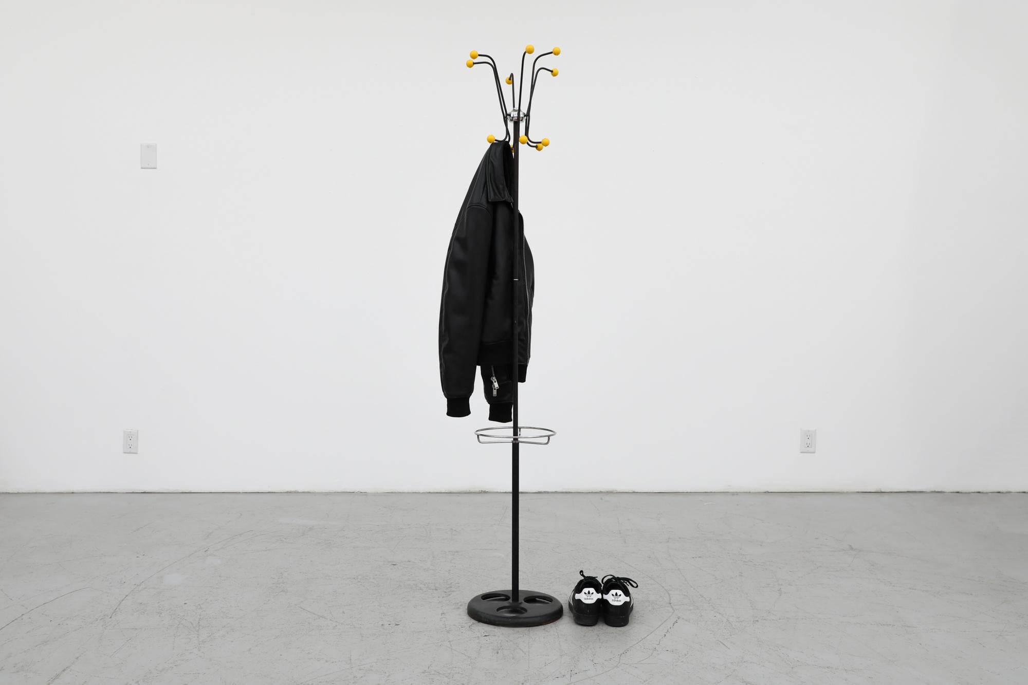 Hago Atomic black enameled metal coat stand with Yellow plastic bobbles and metal ring for umbrellas. In Original Condition with no drip plates and some visible wear consistent with age and use. Other coat stands also available and listed separately.